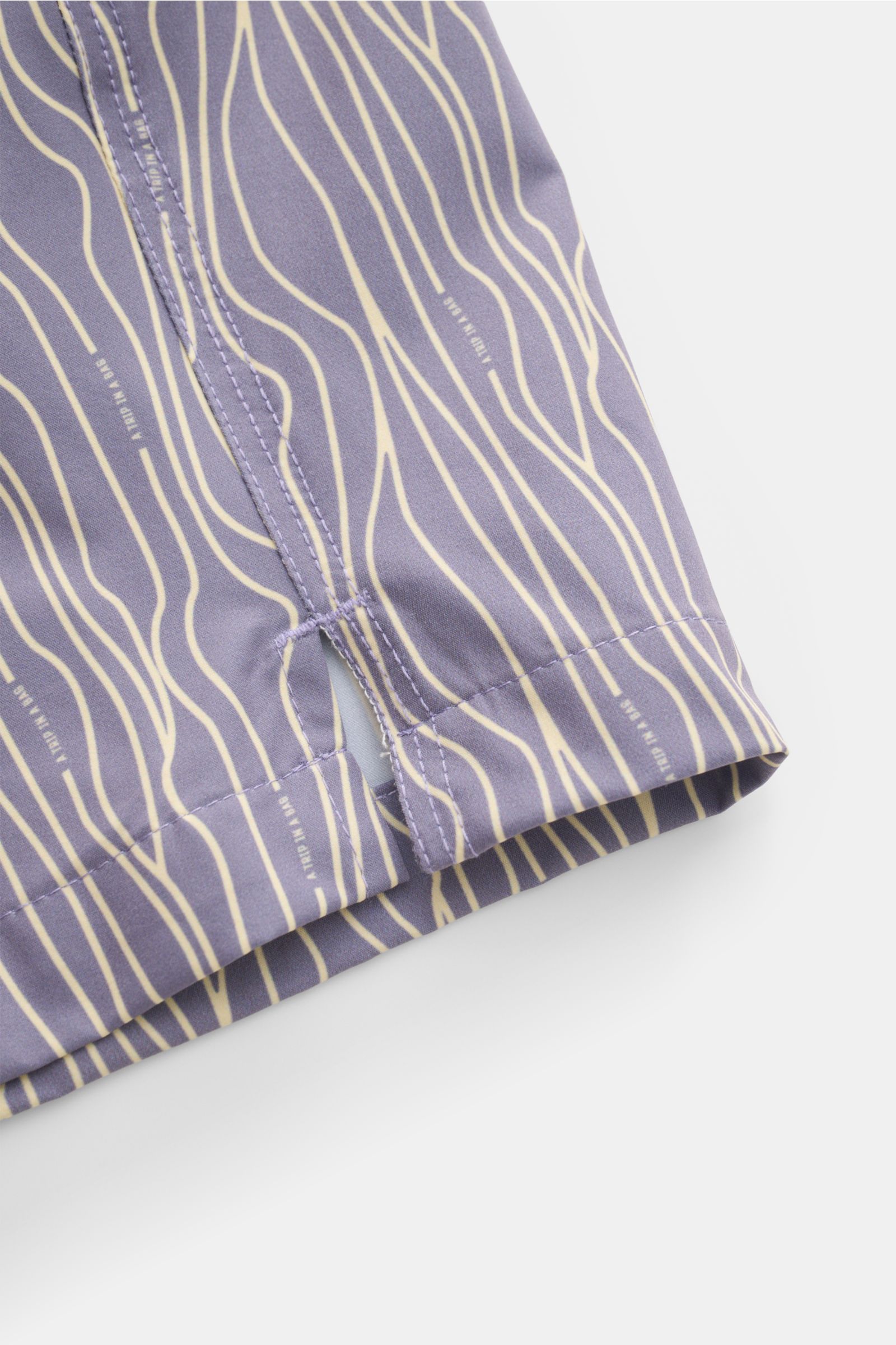 Nahaufnahme der seitlichen Saumschlitze der 04651/ A trip in a bag Badeshorts 'Superkilen' lavender/pastellgelb gemustert mit leichtem, hochwertigem Microfaserstoff.