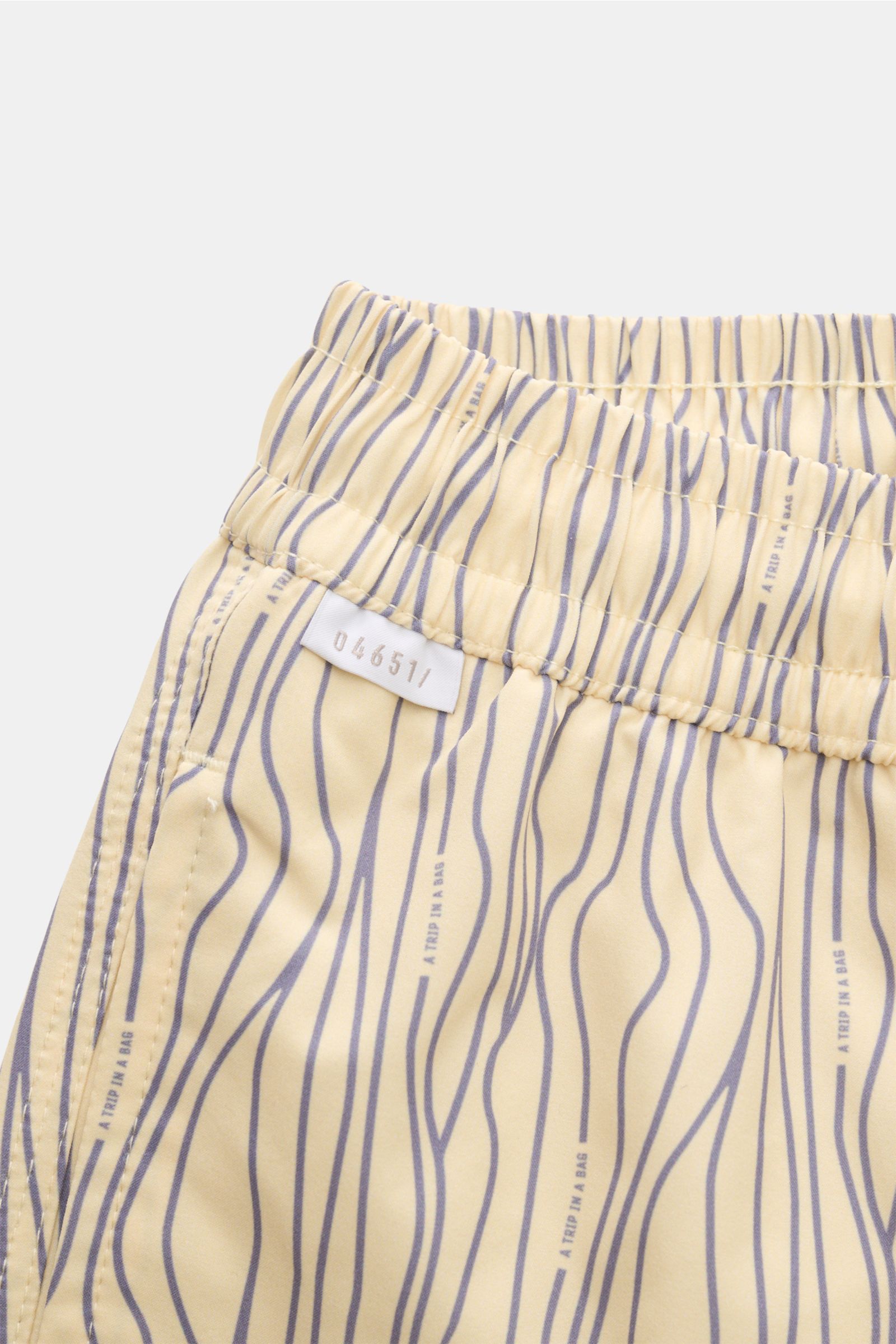 Close-up front-left view of 04651/ A trip in a bag Swim shorts 'Superkilen' pastel yellow/lavender patterned with elastic waistband and side seam pocket.

An eye-catching piece for summer: With their all-over print inspired by Copenhagen’s 'Superkilen'