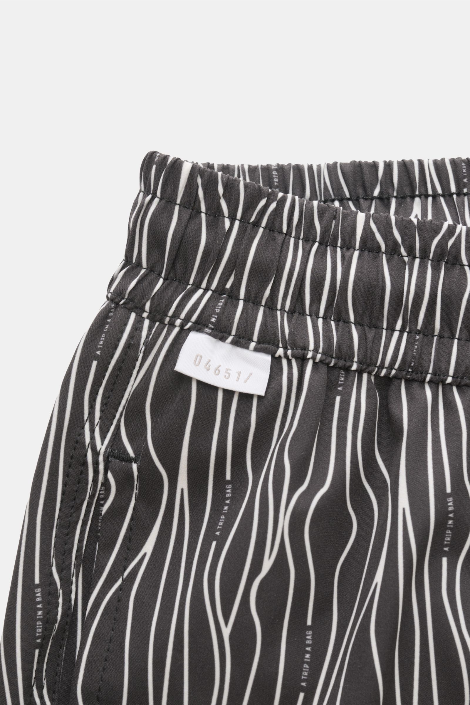Close-up view of the elastic waistband and side pocket of 04651/ A trip in a bag Swim shorts 'Superkilen' black/white patterned with all-over Copenhagen Superkilen park-inspired print. 

An eye-catching piece for summer: With their all-over print inspi