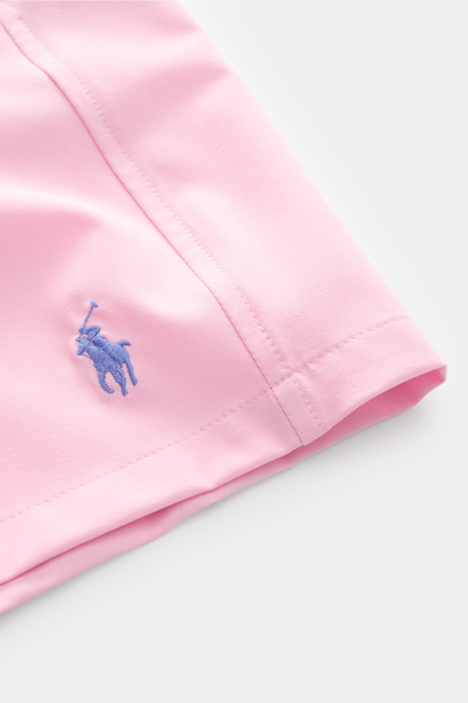 Nahaufnahme der Polo Ralph Lauren Badeshorts 'Traveler' rosé, Perspektive auf das Bein mit sichtbarem blauen Logo-Stitching, aus schnell trocknender Microfaser, Regular Fit, elastischem Bund, Taschen und Mesh-Futter, ideal für sonnige Reisen.