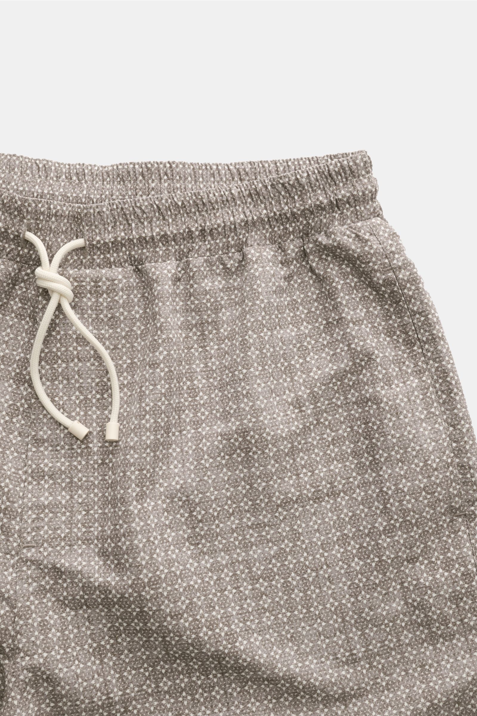 Close-up front view of Brunello Cucinelli Badeshorts oliv/creme gemustert with elastic waistband and drawstring, featuring floral pattern.

Luxuriös entspannen: Mit ihrem floralen Muster sowie dezenten Logo-Stitching werden die Badeshorts von BRUNELLO 