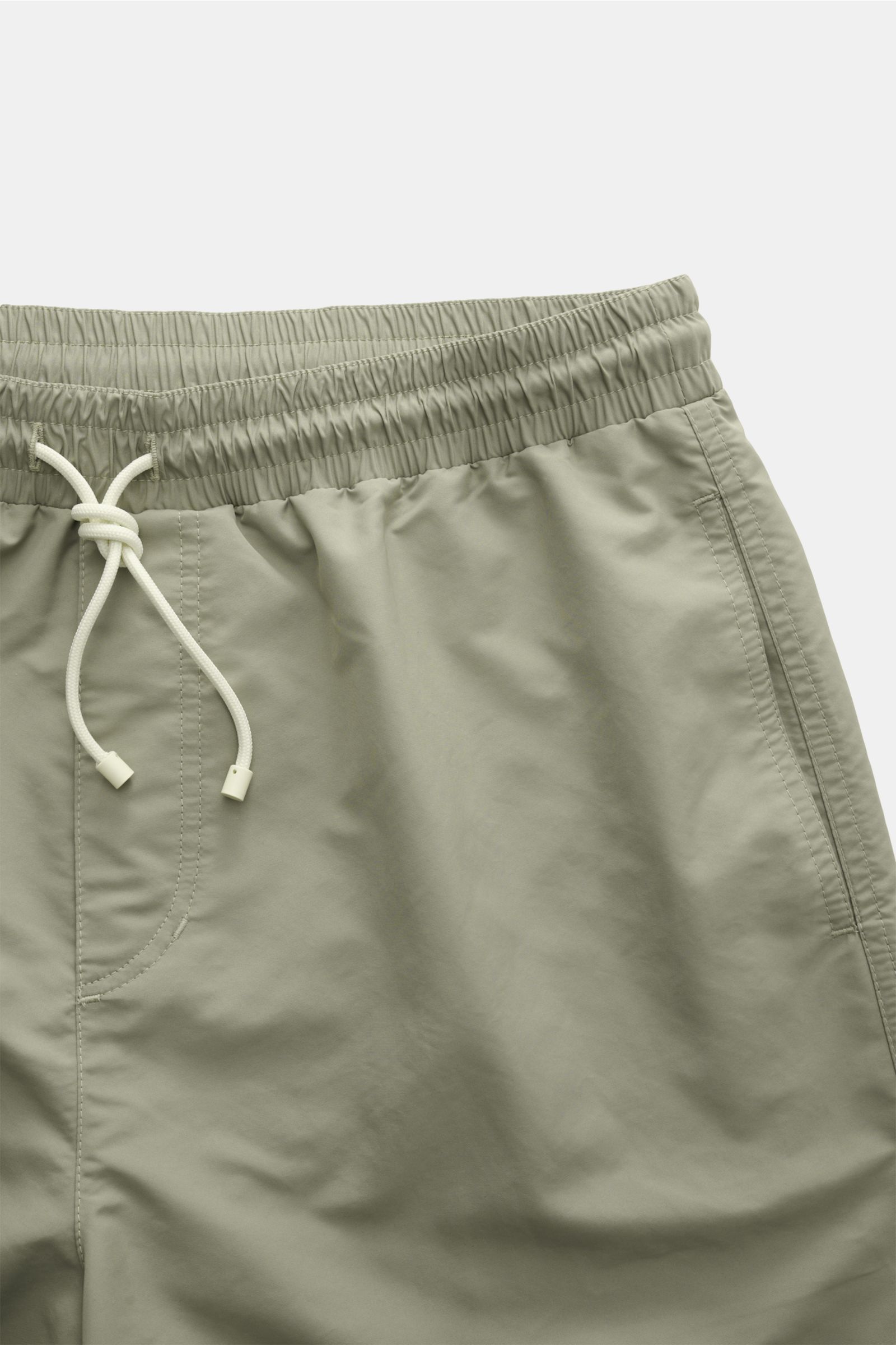 Close-up front view of Brunello Cucinelli Badeshorts salbei in sage green with elastic waistband and white drawstring, smooth fabric.

Description: Luxuriös entspannen: Mit ihrem dezenten Logo-Stitching werden die Badeshorts von BRUNELLO CUCINELLI zum 