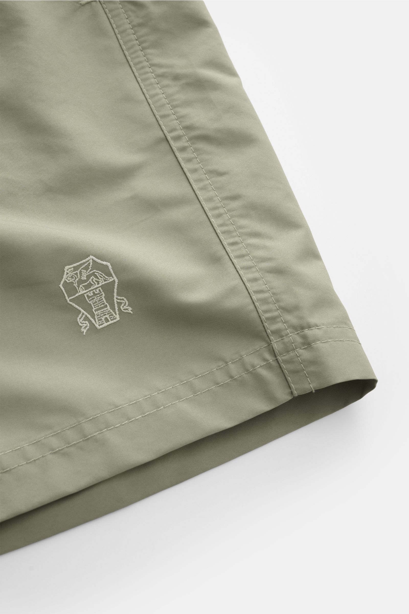 Close-up angled view of light sage green Brunello Cucinelli Badeshorts salbei showing fine stitching and subtle logo embroidery on the thigh. Luxuriös entspannen: Mit ihrem dezenten Logo-Stitching werden die Badeshorts von BRUNELLO CUCINELLI zum stilvo