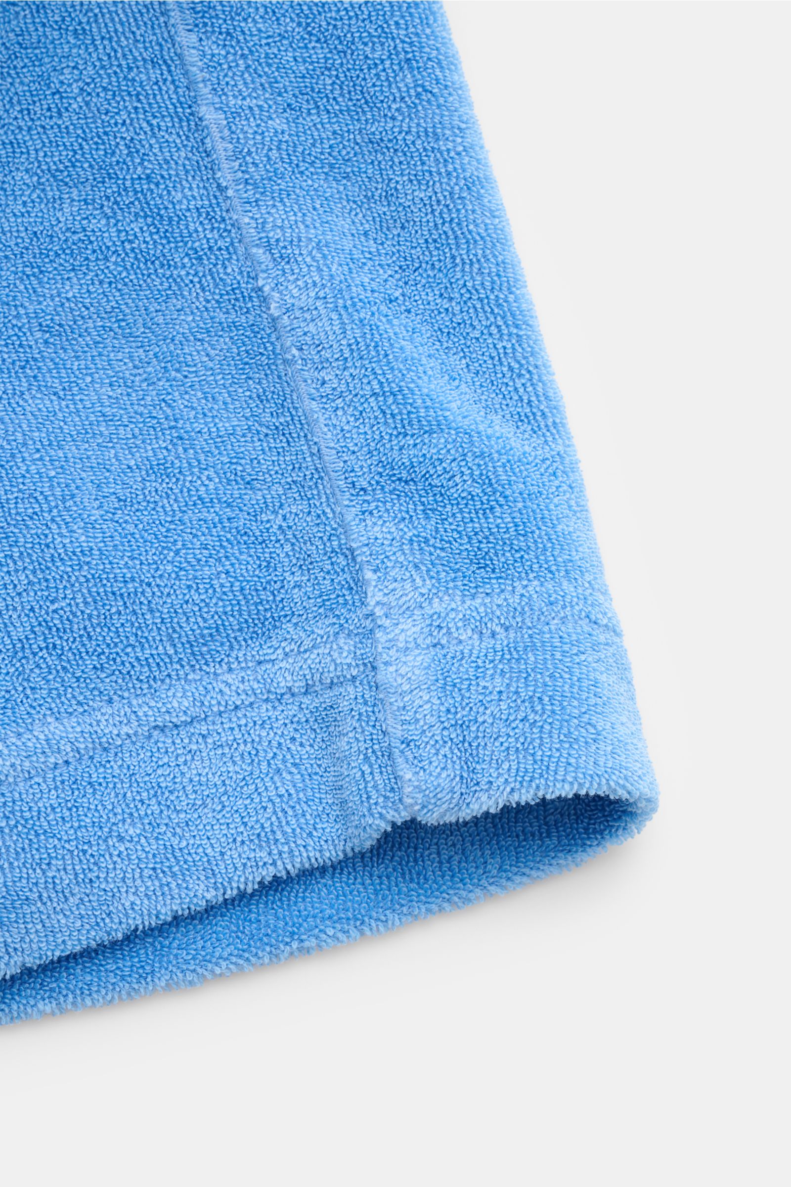 Close-up view of the hem of the 04651/ A trip in a bag Kinder Frottee-Bermudas 'Kids Terry Bermuda' blau in soft blue terry cloth. Ein Kleidungsstück, welches für den perfekten Strandtag nicht fehlen darf: Aus der 'Oyster'-Kollektion präsentiert 04651/ A 