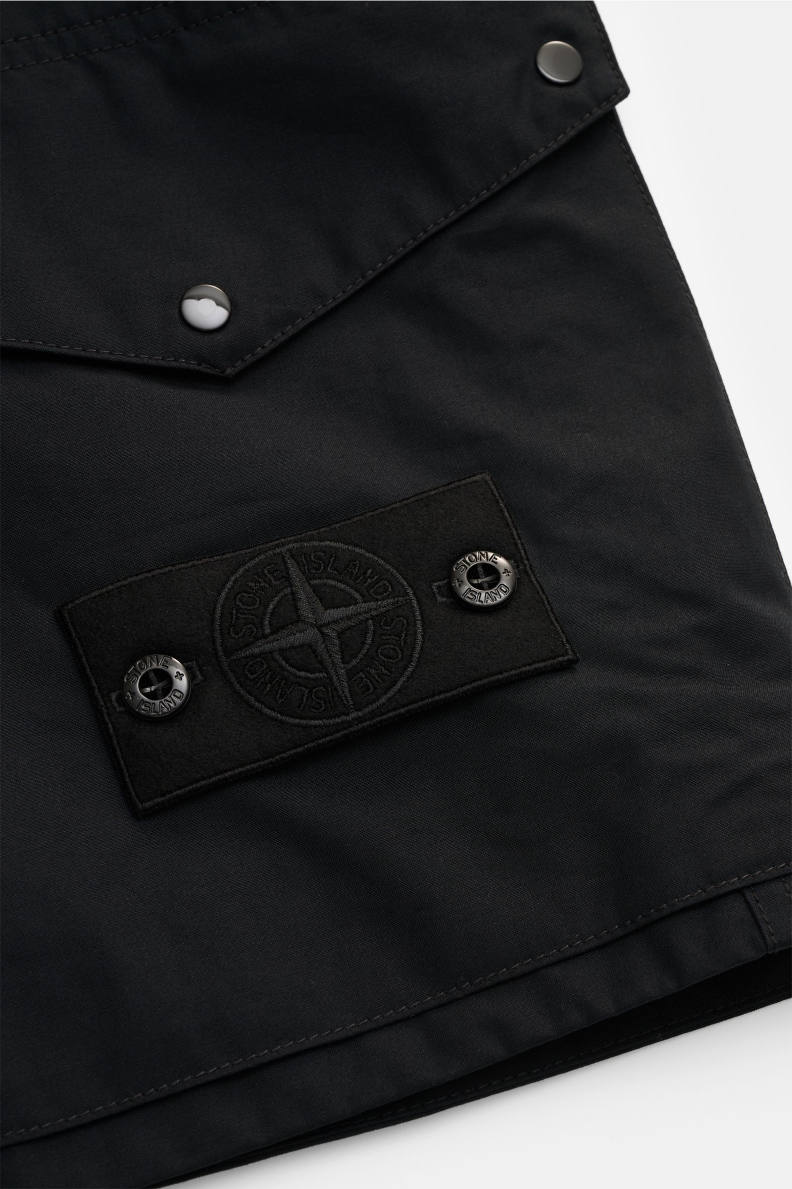Alt tag (125 characters max): Close-up front view of Stone Island Shorts 'Ghost' black showing fabric, buttons, and signature compass badge detail.

Description: 
Modern utility design: These STONE ISLAND shorts from the 'Ghost' Capsule Collection are 