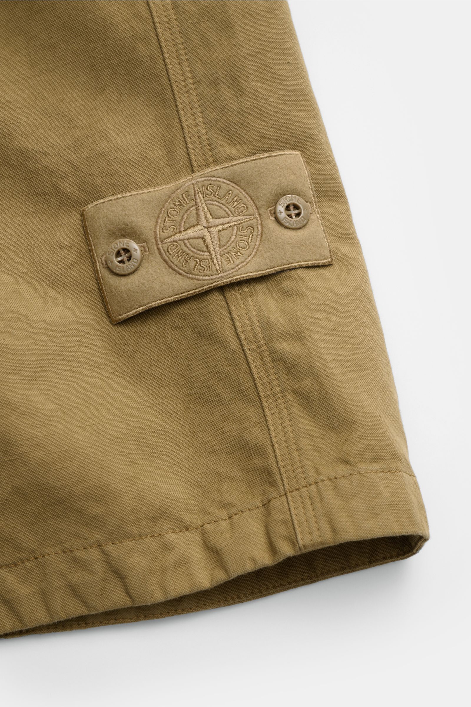 Close-up view of the Stone Island Shorts 'Ghost Piece' khaki showing the tonal compass badge on durable cotton-linen canvas fabric.

Description: Monochromes Sommer-Piece: die komfortablen Shorts von STONE ISLAND aus der 'Ghost Collection' wurden aus robu