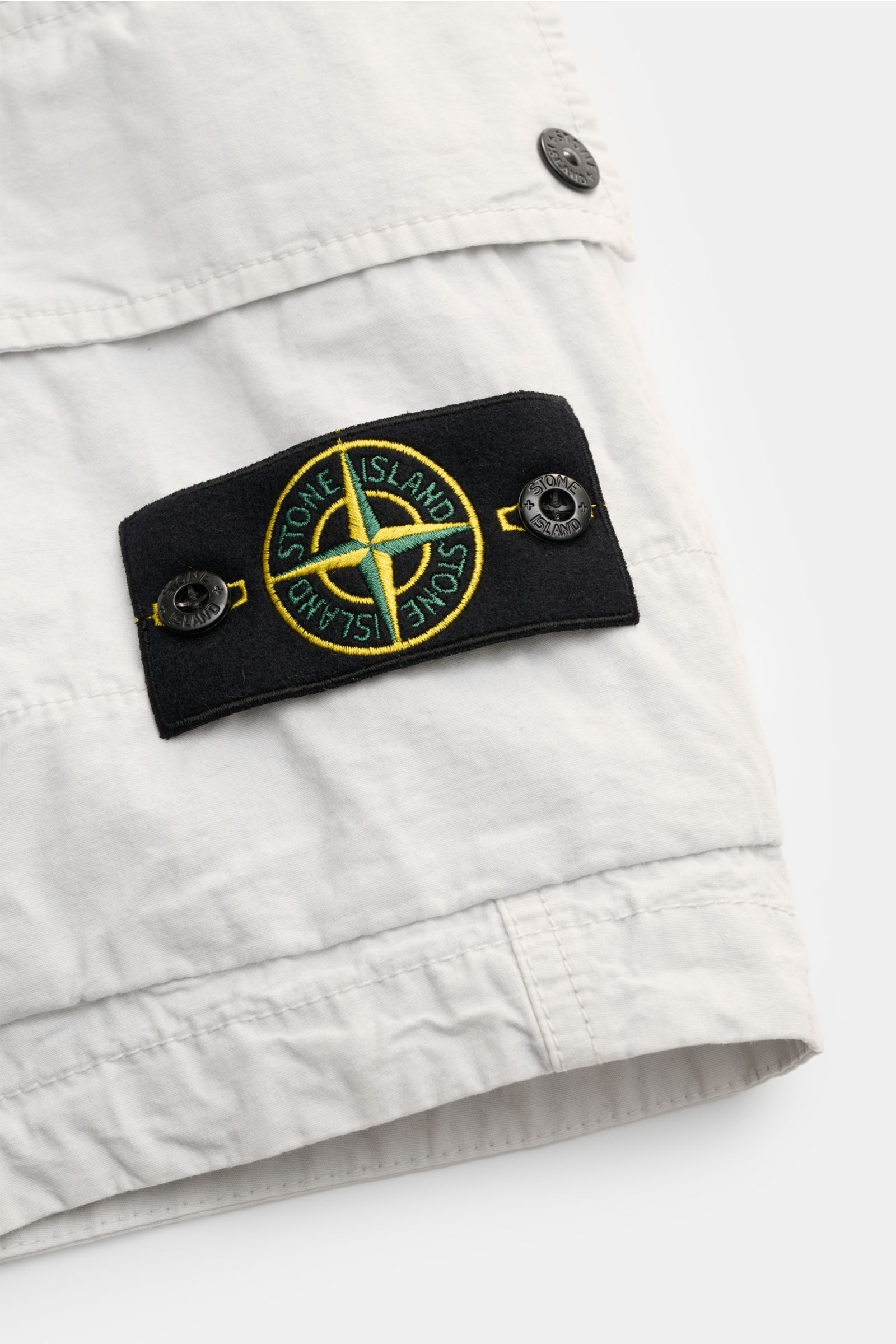 Stone Island Cargo-Bermudas hellgrau, Detailansicht seitlich, reine Baumwolle, weicher Griff, Kompass-Badge, Cargotasche mit Druckknöpfen.