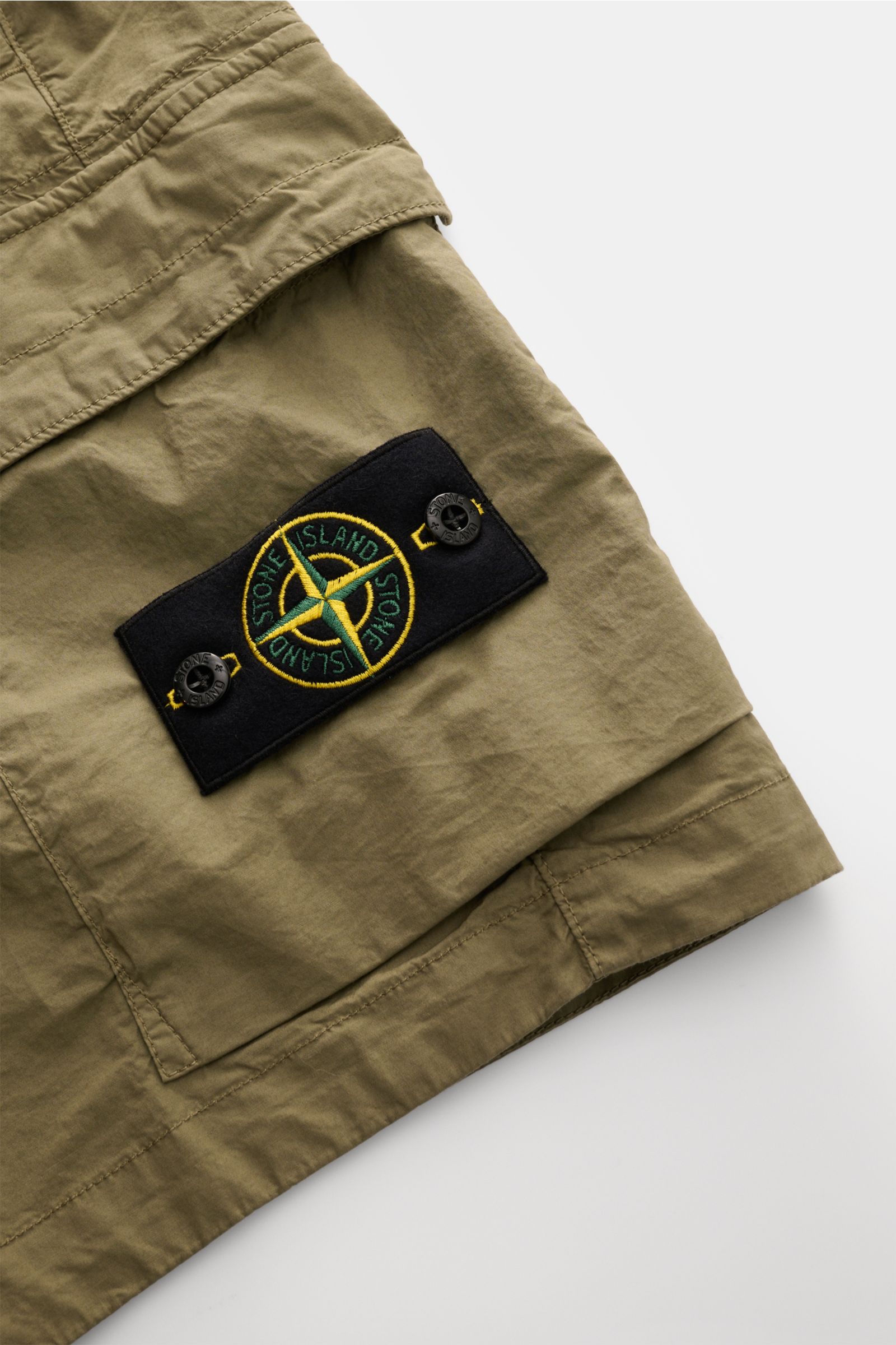 Stone Island Cargo-Shorts oliv im Nahaufnahmefoto von der Seite, mit elastischer Baumwolle, Cargotaschen und markentypischem Kompass-Badge.