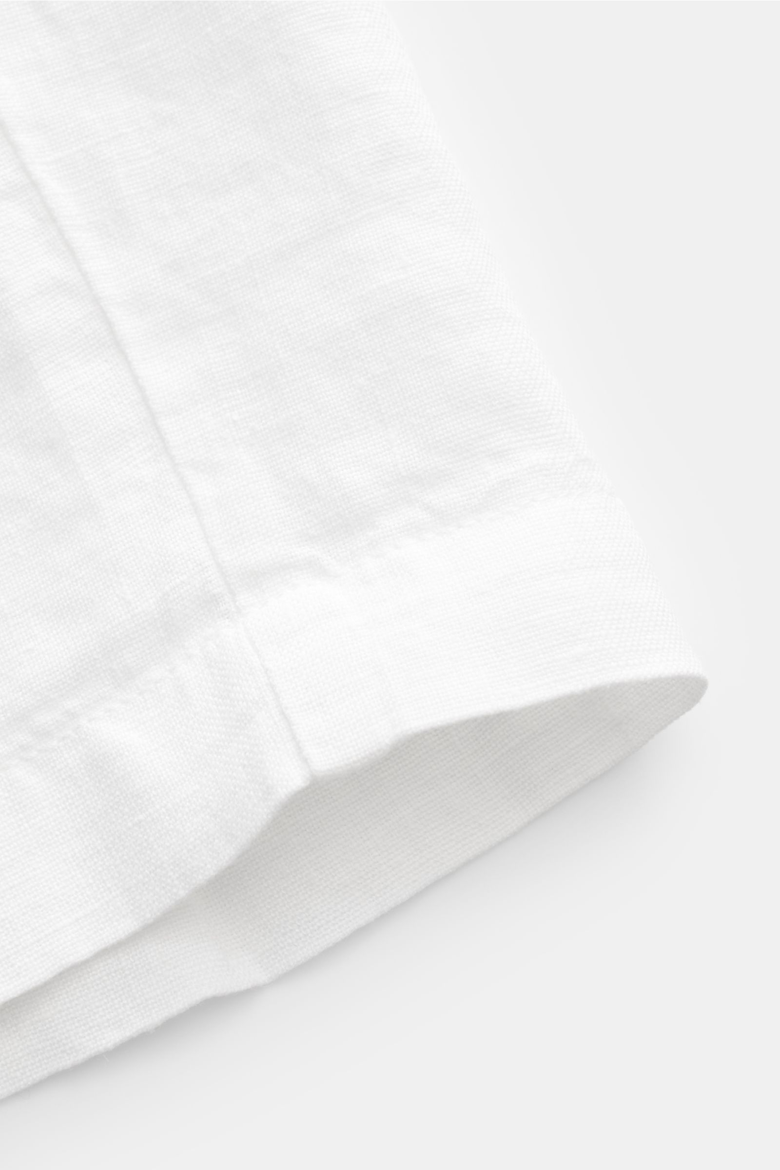 Close-up front-side view of the hem and texture of 04651/ A trip in a bag Linen bermudas 'Linen Bermuda' white, showcasing pure linen fabric and soft feel. These airy Bermudas by 04651/ A TRIP IN A BAG are a must-have for your next beach holiday. The flex