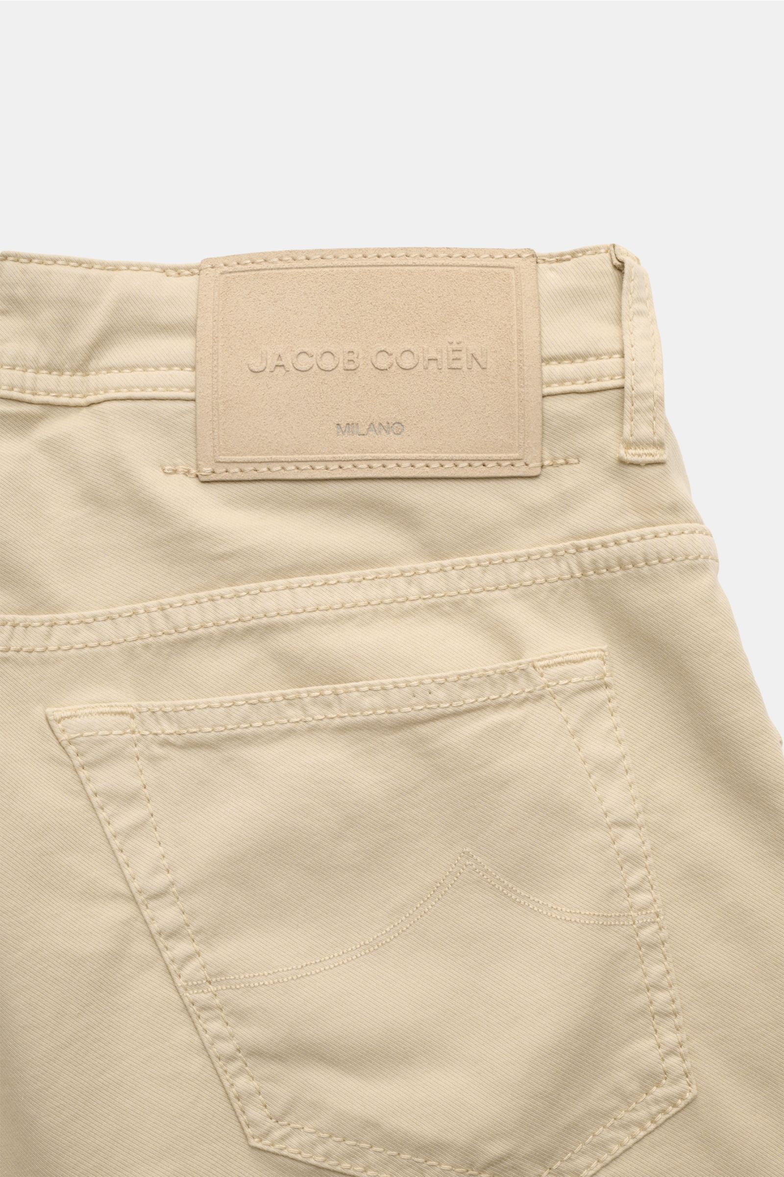 Close-up rear view of Jacob Cohen Bermudas 'Lou' beige showing back pocket and embossed leather brand patch on lightweight cotton-lyocell fabric.

Summer as it should be: The 'Lou' bermudas by JACOB COHEN combine the distinctive style of the Italian de