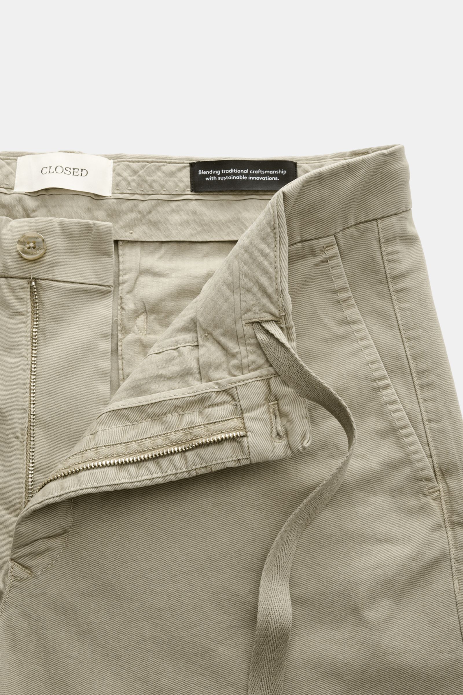 Nahaufnahme der geöffneten Closed Shorts taupe aus Baumwoll-Twill mit Reißverschluss, Bundknopf, Tunnelzug und französischen Taschen.