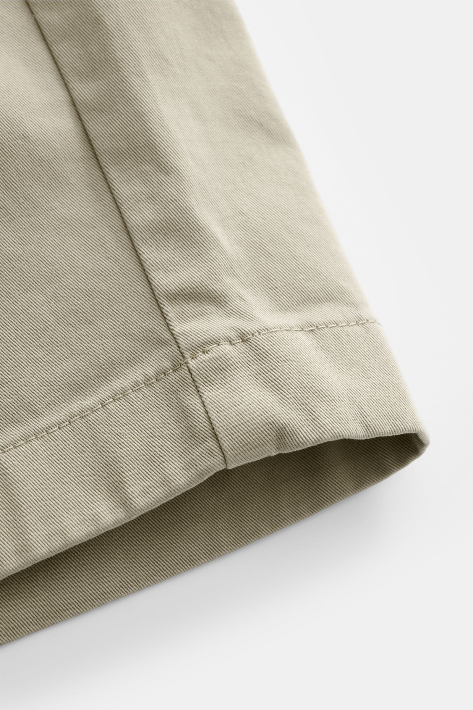 Nahaufnahme der leicht elastischen Baumwoll-Twill-Closed Shorts taupe im Regular Fit, Detailansicht des Saums aus schräger Perspektive.