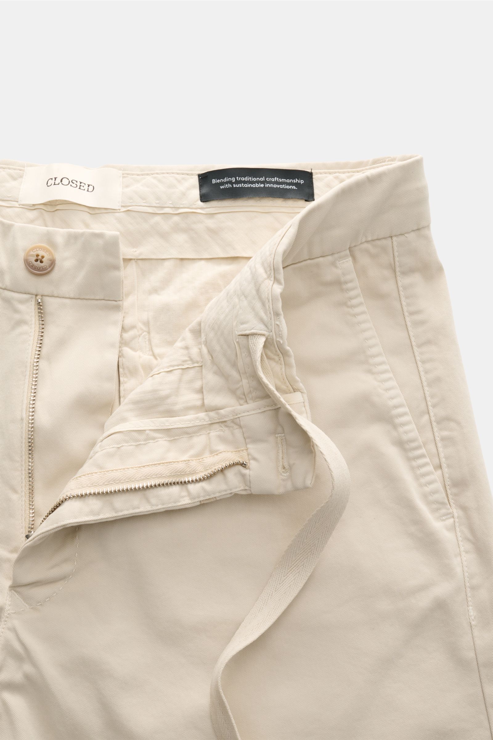 Nahaufnahme der geöffneten Closed Shorts sand aus leicht elastischem Baumwoll-Twill, Front mit Reißverschluss, Bundknopf und Tunnelzug.