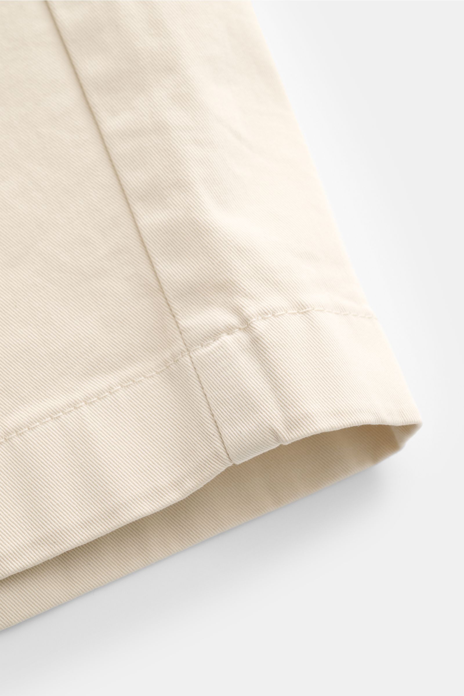 Close-up der sandfarbenen Closed Shorts sand aus Baumwoll-Twill mit feiner Struktur, sichtbarer Naht und Regular Fit, seitliche Perspektive.