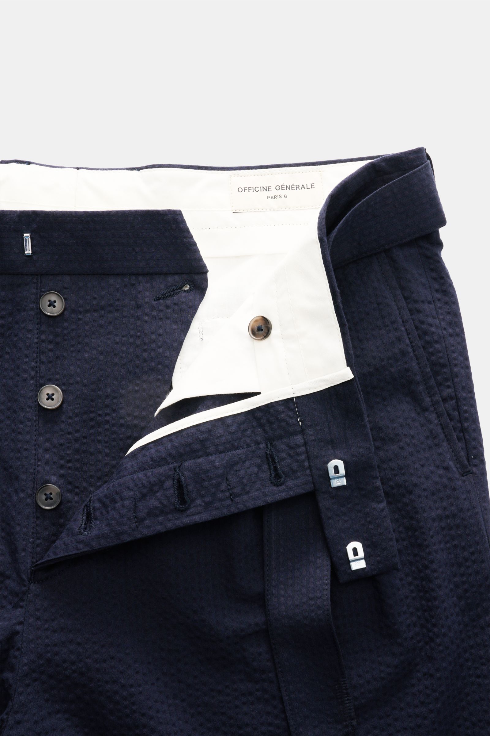 Officine Générale Seersucker-Shorts 'Georges' navy, Detailansicht offen von oben mit leichter Baumwoll-Seersucker-Struktur, doppelter Bundfalte und Gürtel.
