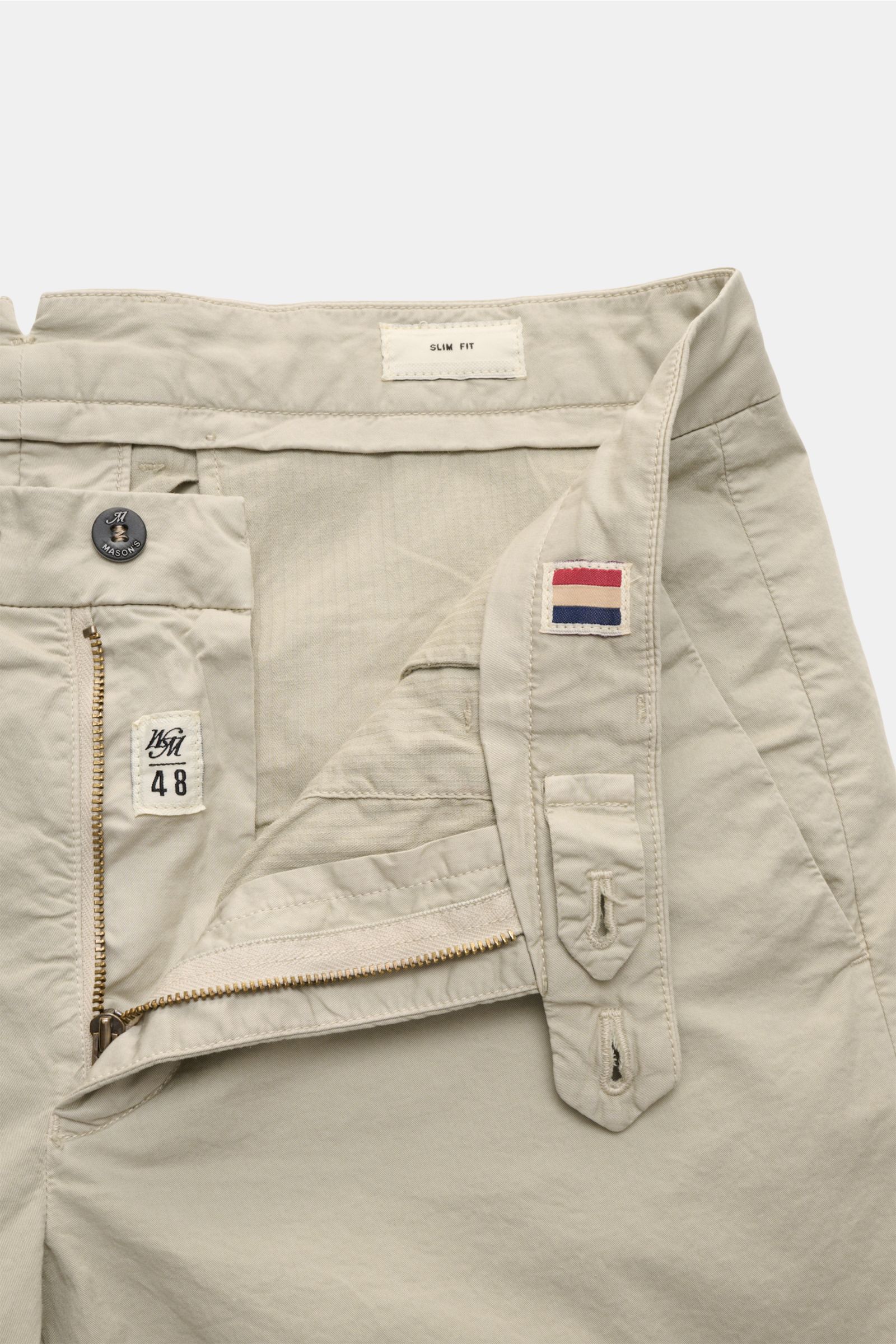 Nahaufnahme der geöffneten Mason's Shorts 'Torino' beige, fotografiert von oben, zeigt elastischen Baumwolltwill, Reißverschluss, Bundknopf, französische Taschen und fixierten Saumaufschlag.