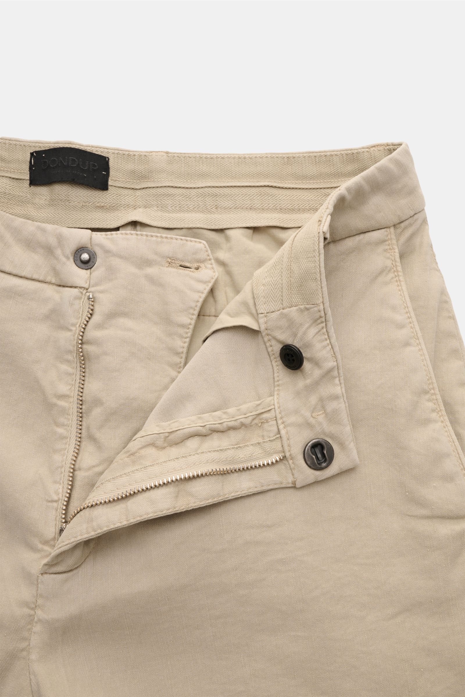 Close-up front view of Dondup Shorts 'Manheim' beige with open zip and slide-button, showing fabric texture and waistband label. Enjoy carefree days in the warm weather – the 'Manheim' shorts by DONDUP are the perfect choice for summer outfits. Made from 