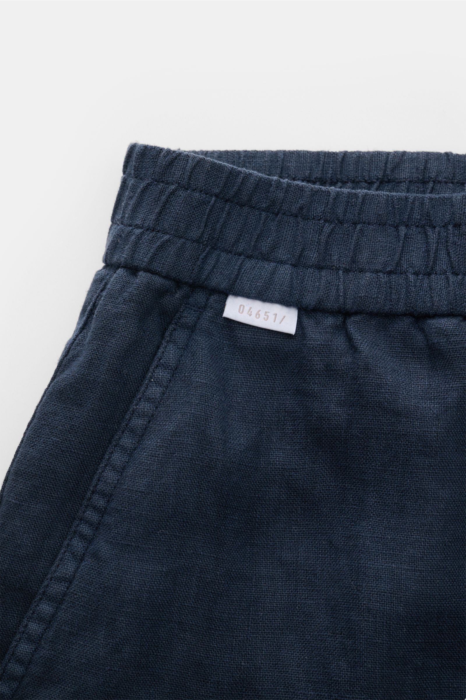 Nahaufnahme der elastischen Bundpartie der 04651/ A trip in a bag Leinenshorts navy aus luftigem Leinen mit Weblabel, französischer Tasche.