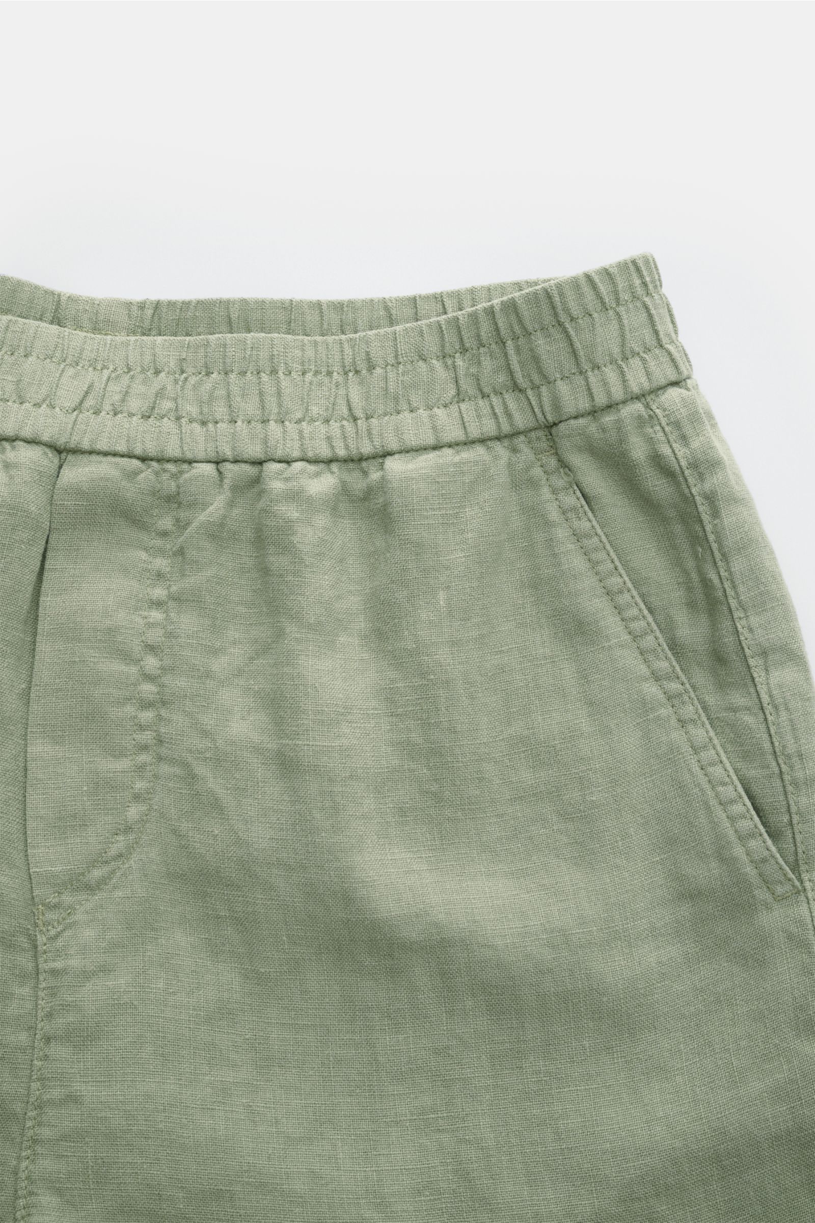 Close-up front view of 04651/ A trip in a bag Linen shorts sage showing elastic waistband and French pocket in soft, airy linen fabric.

With this airy model, 04651/ A TRIP IN A BAG presents a comfortable pair of pure linen shorts that are the perfect 