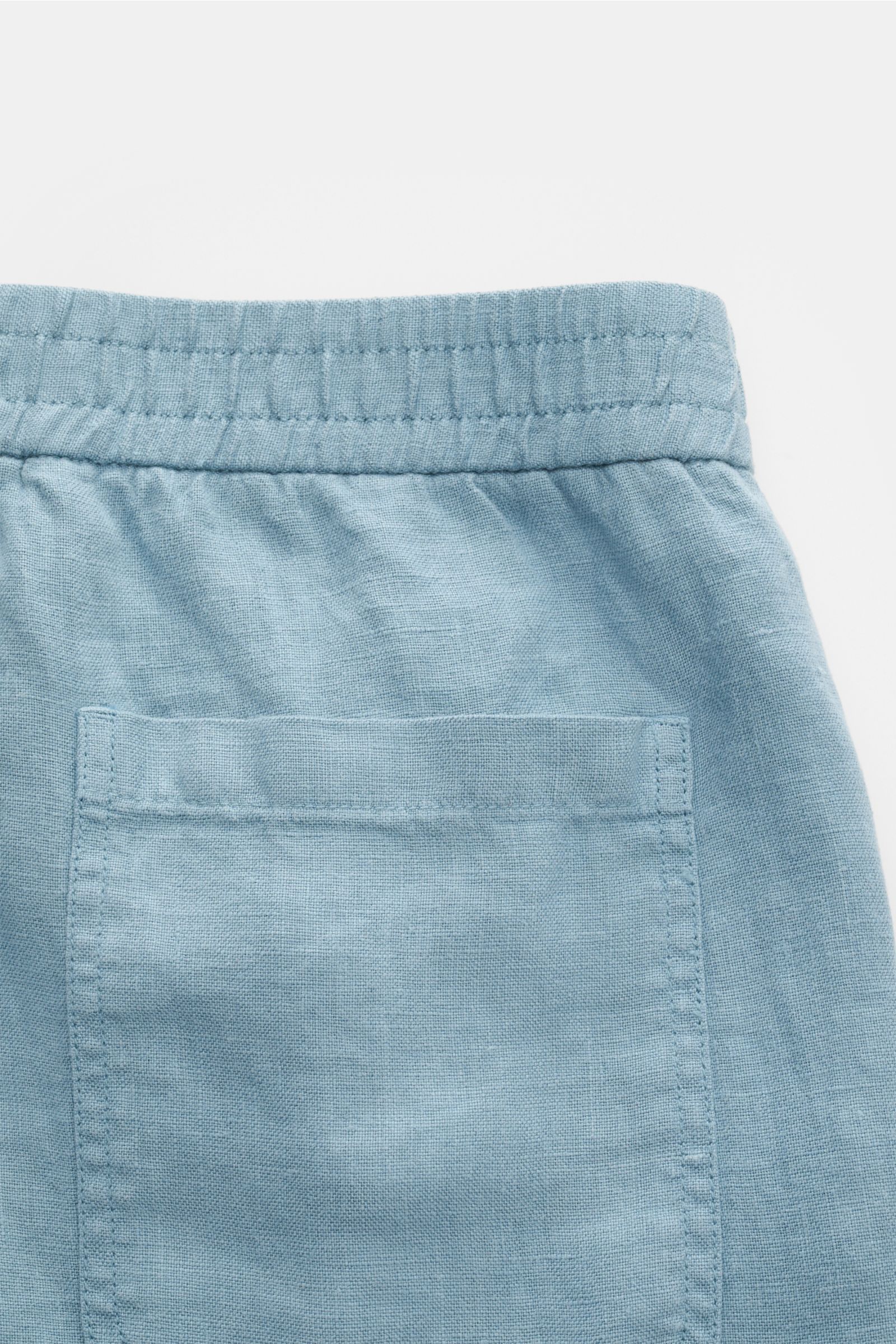 Rückansicht der rauchblauen 04651/ A trip in a bag Leinenshorts aus weichem, luftigen Leinen mit elastischem Bund, Gesäßtasche und kleinem Weblabel.