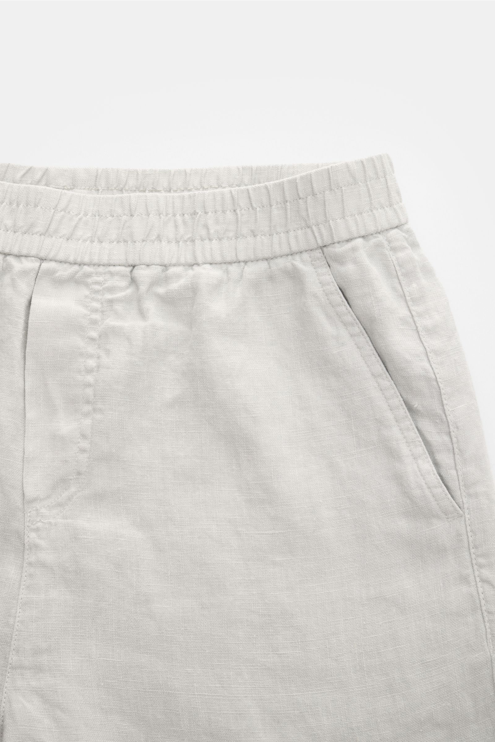 04651/ A trip in a bag Leinenshorts hellgrau in Nahaufnahme von vorne, mit elastischem Bund, französischen Taschen, weichem Leinenstoff und kleinem Weblabel.