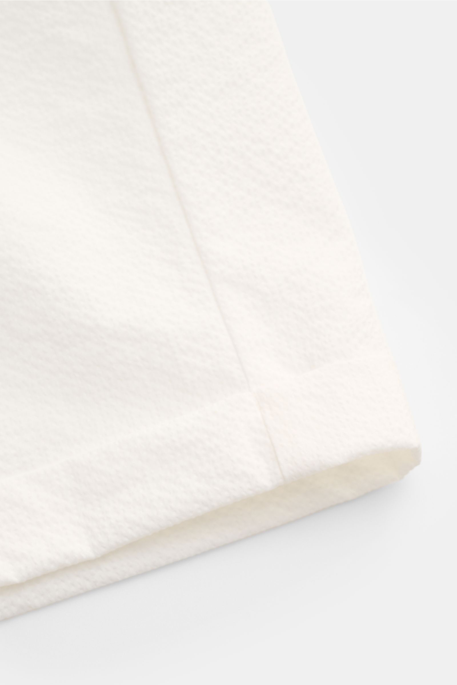 Close-up side view of the 04651/ A trip in a bag Seersucker shorts white, showing textured seersucker fabric, fixed hem turn-up, and subtle seams. With this classic model, 04651/ A TRIP IN A BAG presents a comfortable pair of shorts in typically textured 