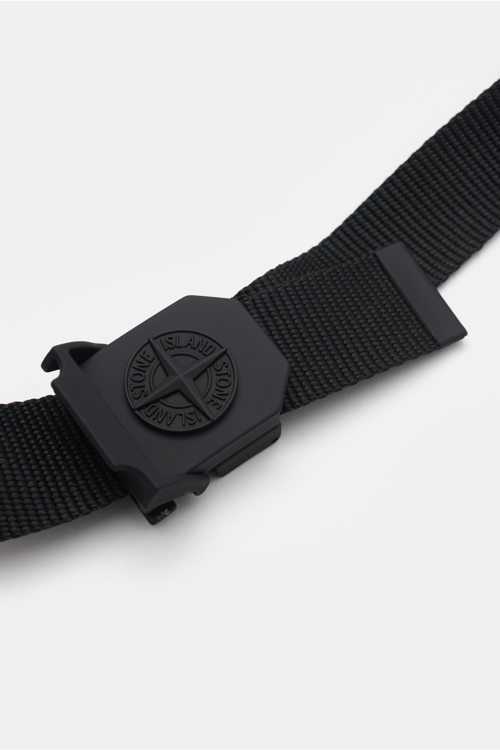 Stone Island Gürtel schwarz aus hochwertiger Microfaser, stufenlos verstellbar, mit gummierter matt-schwarzer Metallkoppelschließe und Kompass-Motiv, seitliche Nahaufnahme.