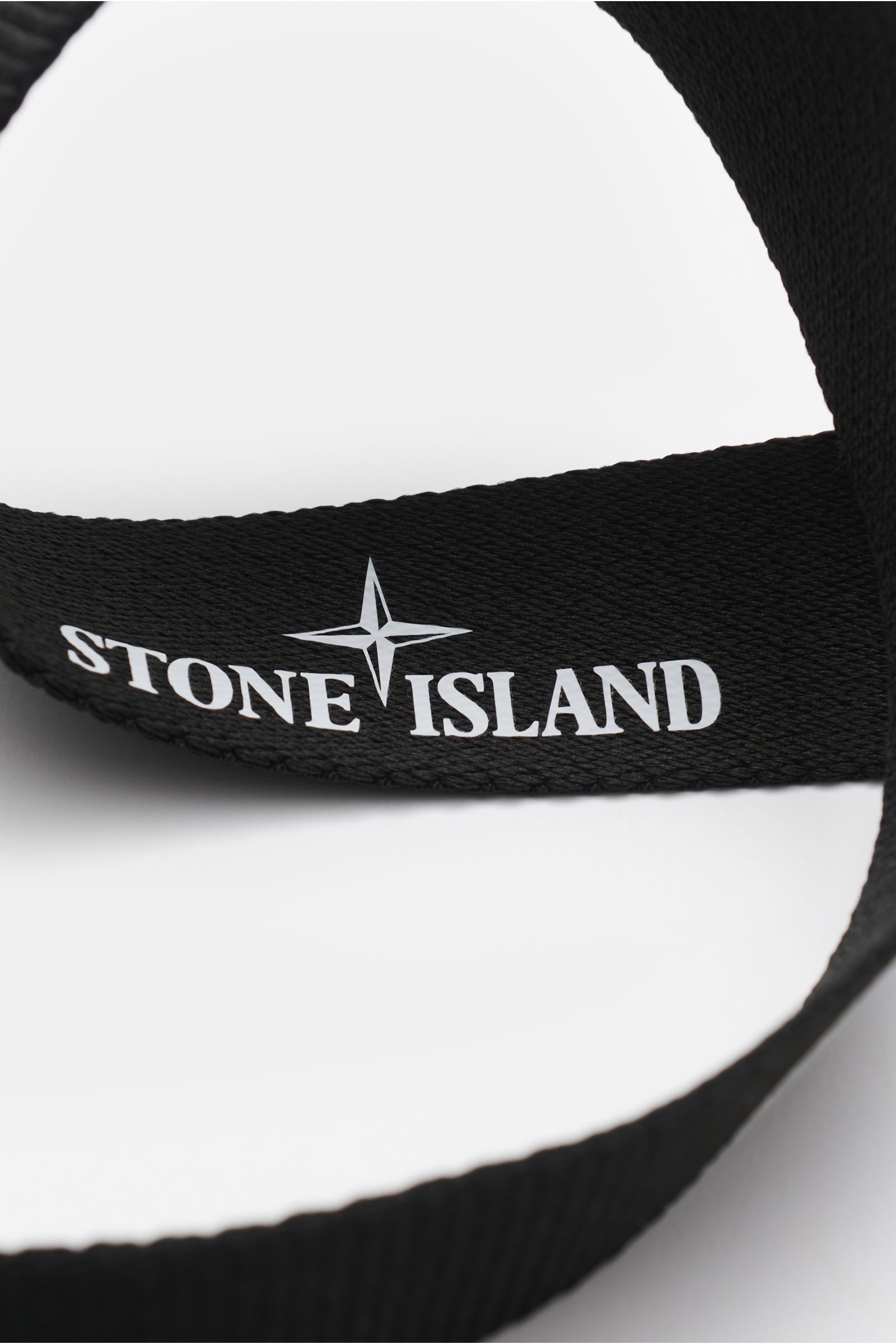 Stone Island Gürtel schwarz aus hochwertiger Microfaser, Detailaufnahme von innen mit weißem Logo, stufenlos verstellbar, gummierte Koppelschließe mit Kompass-Motiv, Made in Italy.