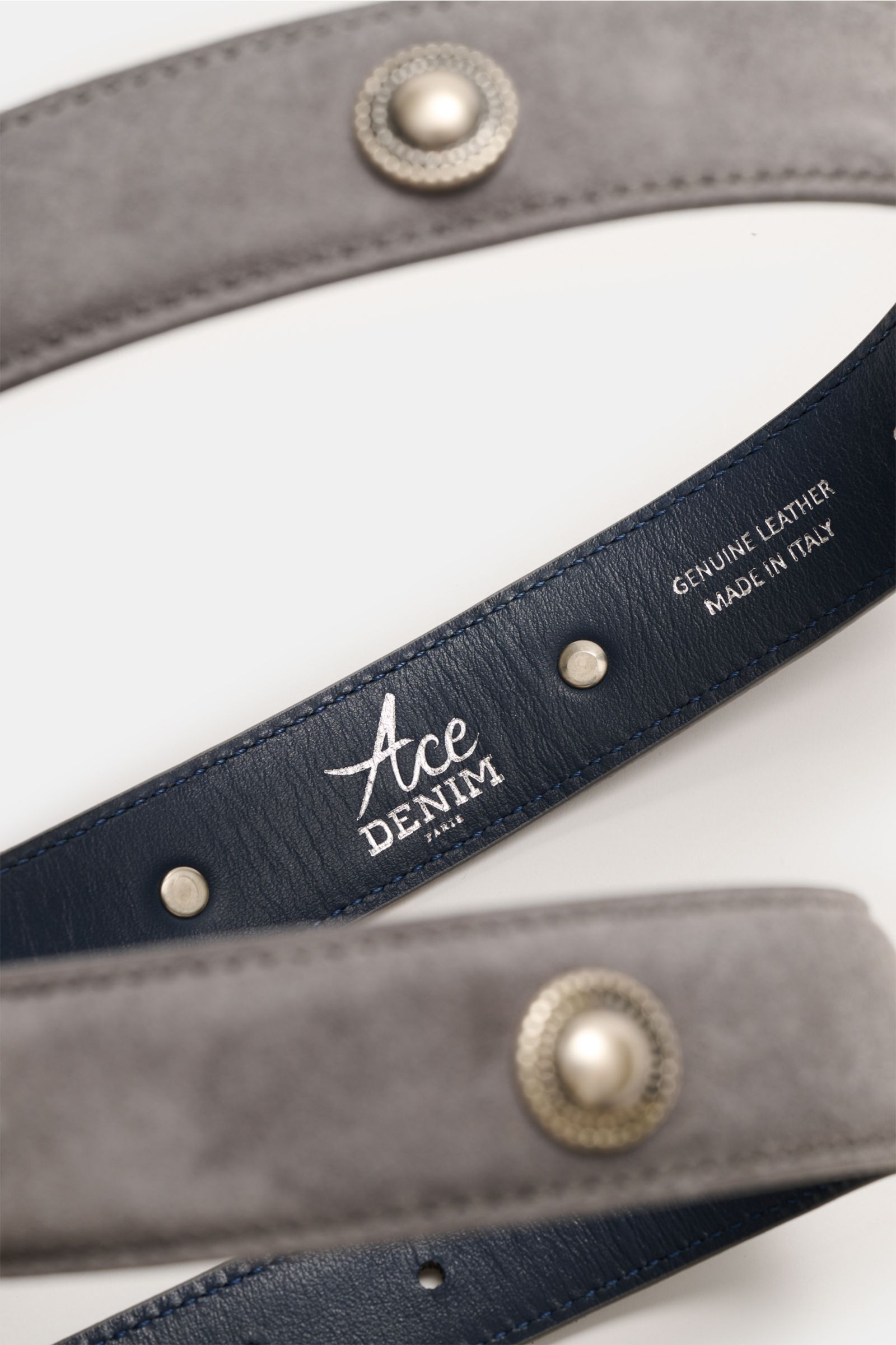 Close-up top-down view of the Ace Denim Veloursleder Gürtel 'Cowboy Belt' grau showing soft grey suede with decorative metal conchos and the navy leather interior stamped with 'Genuine Leather Made in Italy.
