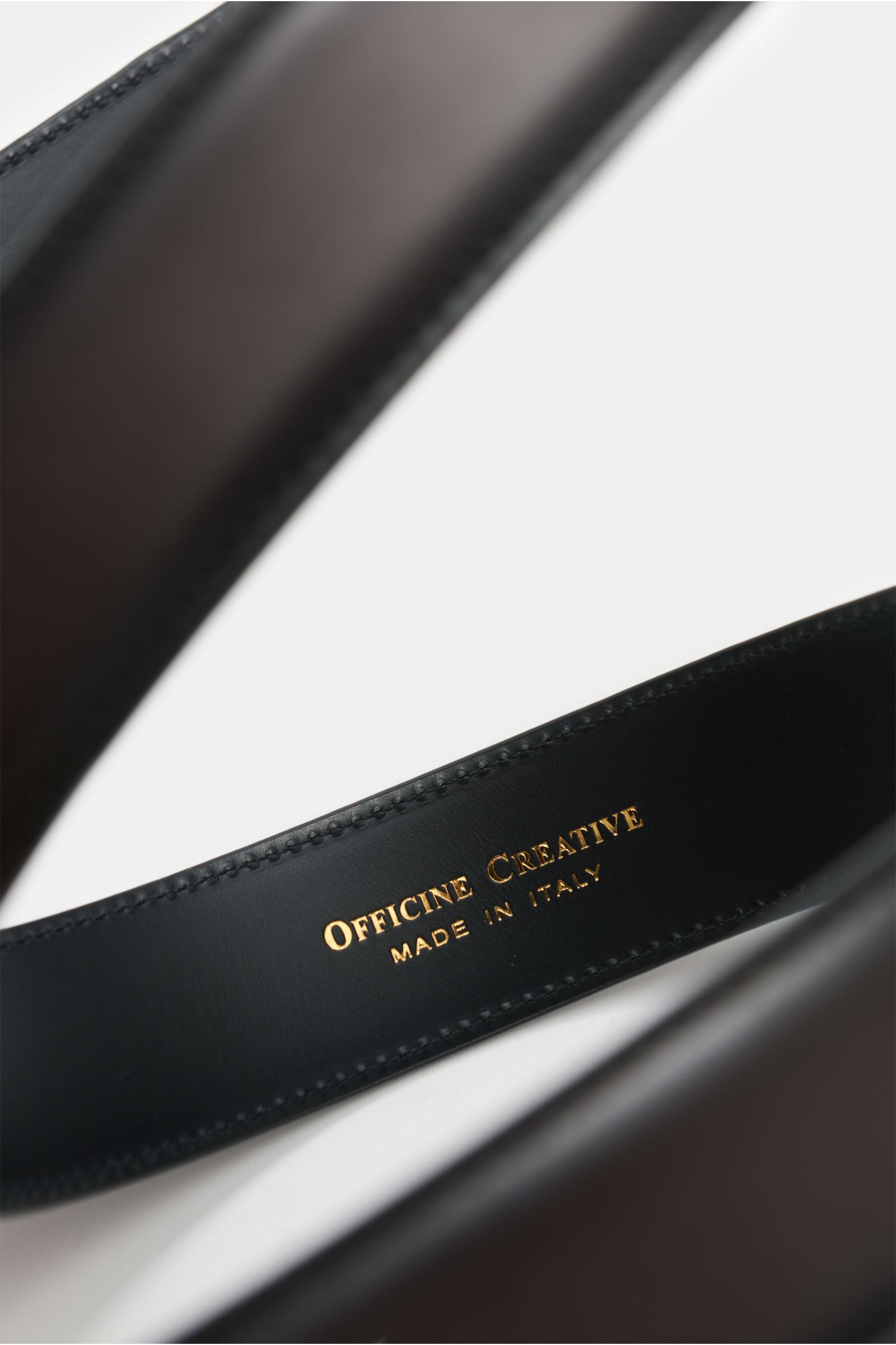 Close-up inside view of the Officine Creative Gürtel dunkelbraun, showcasing elegant smooth leather and gold 'Made in Italy' logo.  
Description: Eleganter Akzentgeber: Der Gürtel von OFFICINE CREATIVE überzeugt mit seinem zeitlosen Design und wird zum