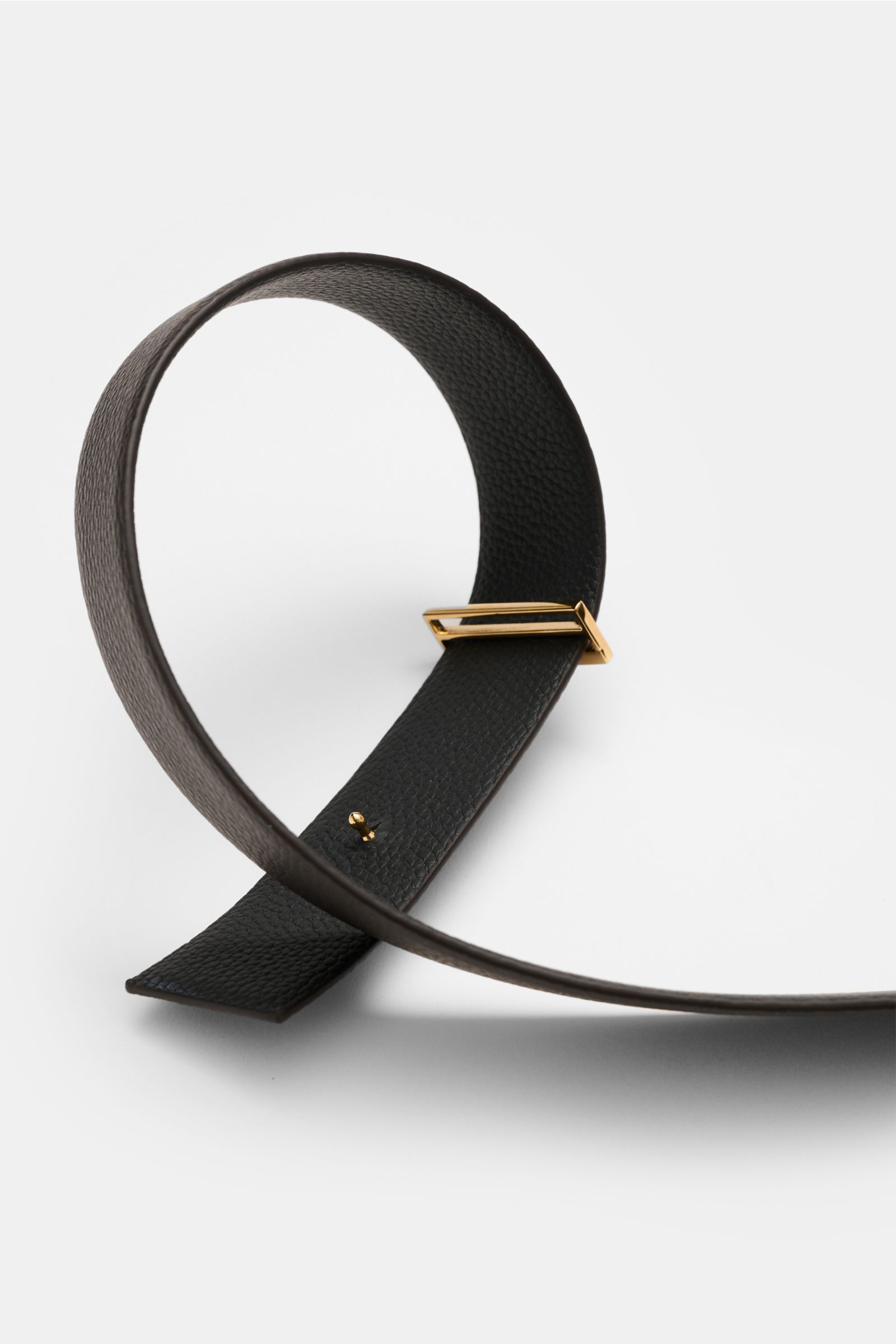 Close-up front angle of Tom Ford Gürtel schwarz/dunkelbraun, showing elegant reversible black and dark brown calf leather with gold brass buckle, textured grain, made in Italy, approx. 3.5 cm wide. Eleganter Eyecatcher: Mit seinem zeitlosen Look wird d