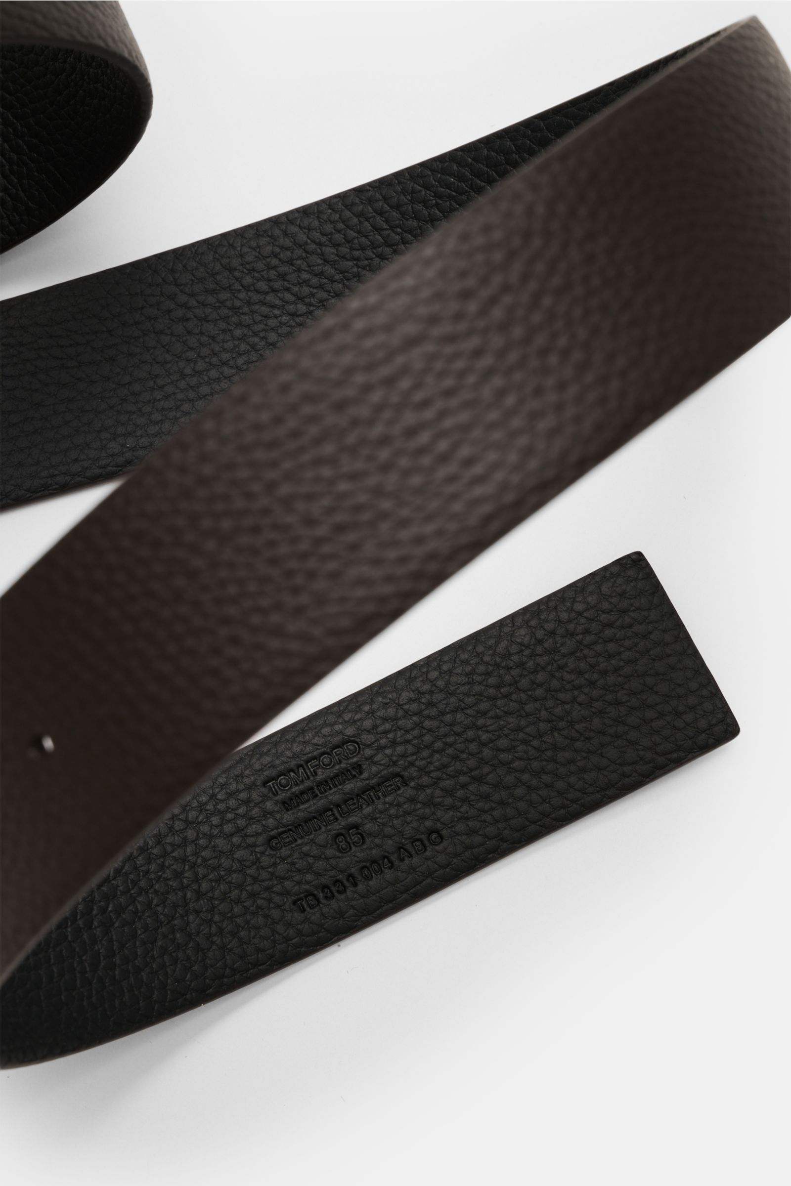 Close-up top view of the Tom Ford Gürtel schwarz/dunkelbraun showing its reversible black and dark brown pebbled calf leather with embossed branding.

Eleganter Eyecatcher: Mit seinem zeitlosen Look wird der TOM FORD Gürtel zum stilvollen Highlight und