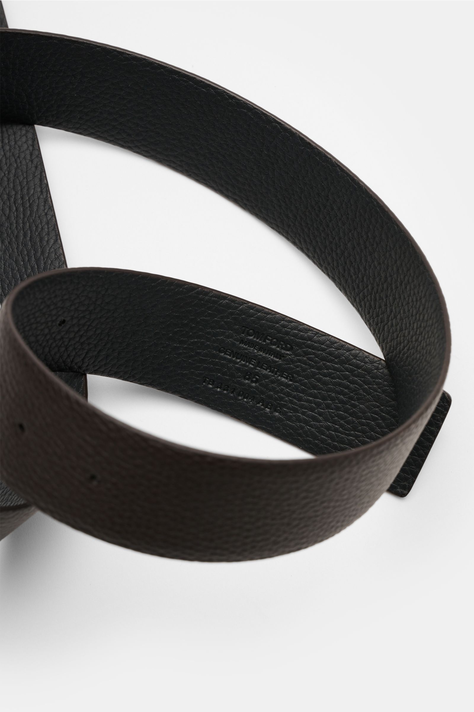 Tom Ford Gürtel schwarz/dunkelbraun shown from a close-up top angle, featuring edles Kalbleder with charakteristische Narbung, wendbar design, silberfarbene Dornschließe aus Messing, Made in Italy, breite ca. 3,5 cm. Eleganter Eyecatcher: Mit seinem ze