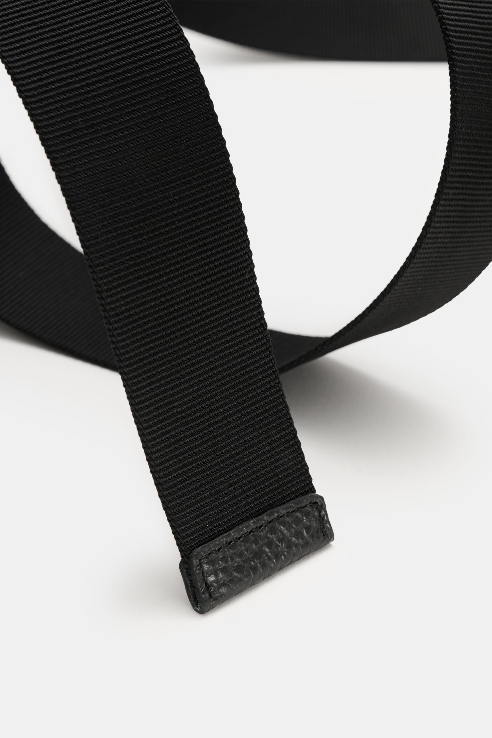 Close-up front angle of Stone Island Gürtel schwarz, a woven belt with high-quality microfiber, adjustable length, and black rubberized metal buckle featuring the iconic compass motif, made in Italy, approx. 4 cm wide.