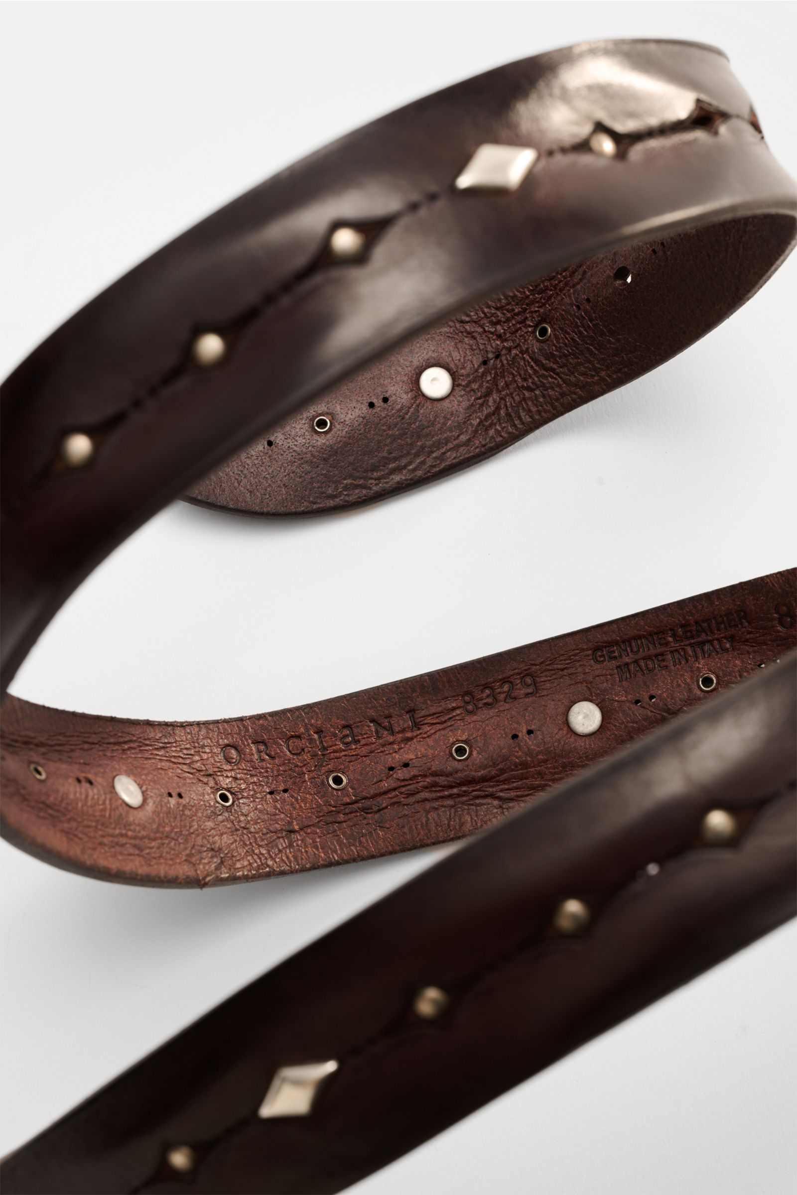 Orciani Gürtel dunkelbraun shown from an angled close-up view, vintage dark brown leather studded belt with brass buckle, 3.5 cm wide, Made in Italy.