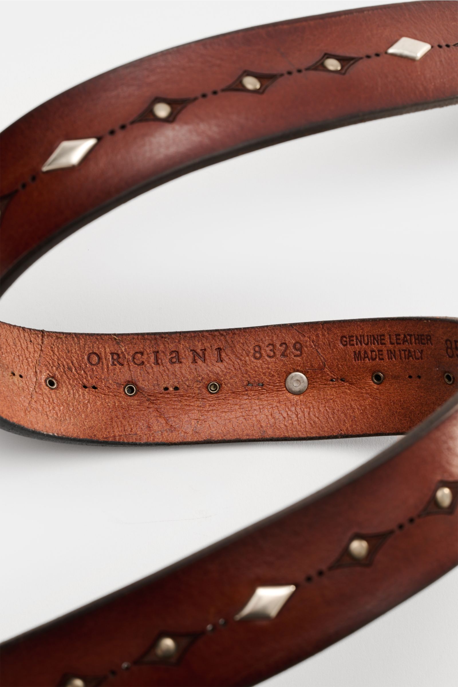 Close-up view of the Orciani Gürtel braun, a luxurious brown leather belt with vintage finish and stud design, showing interior branding.