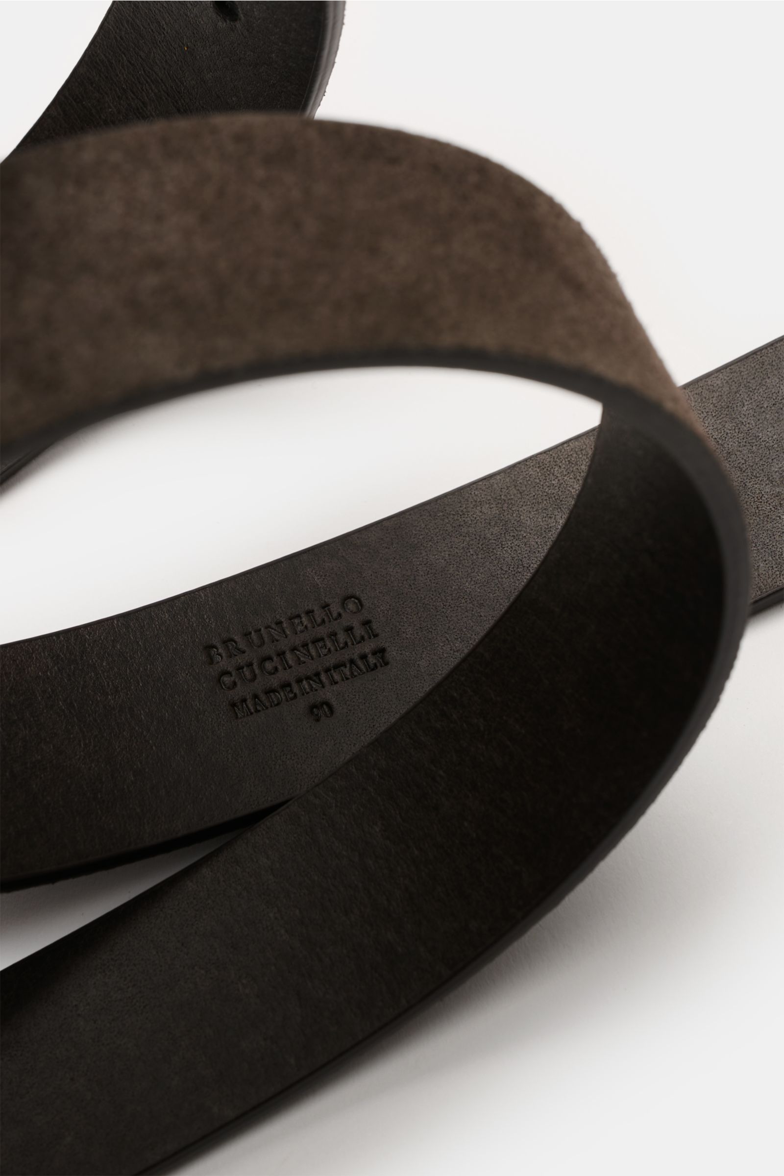 Brunello Cucinelli Veloursleder Gürtel dunkelbraun aus softem Veloursleder, mit silberfarbener Dornschließe, schräg von oben fotografiert.