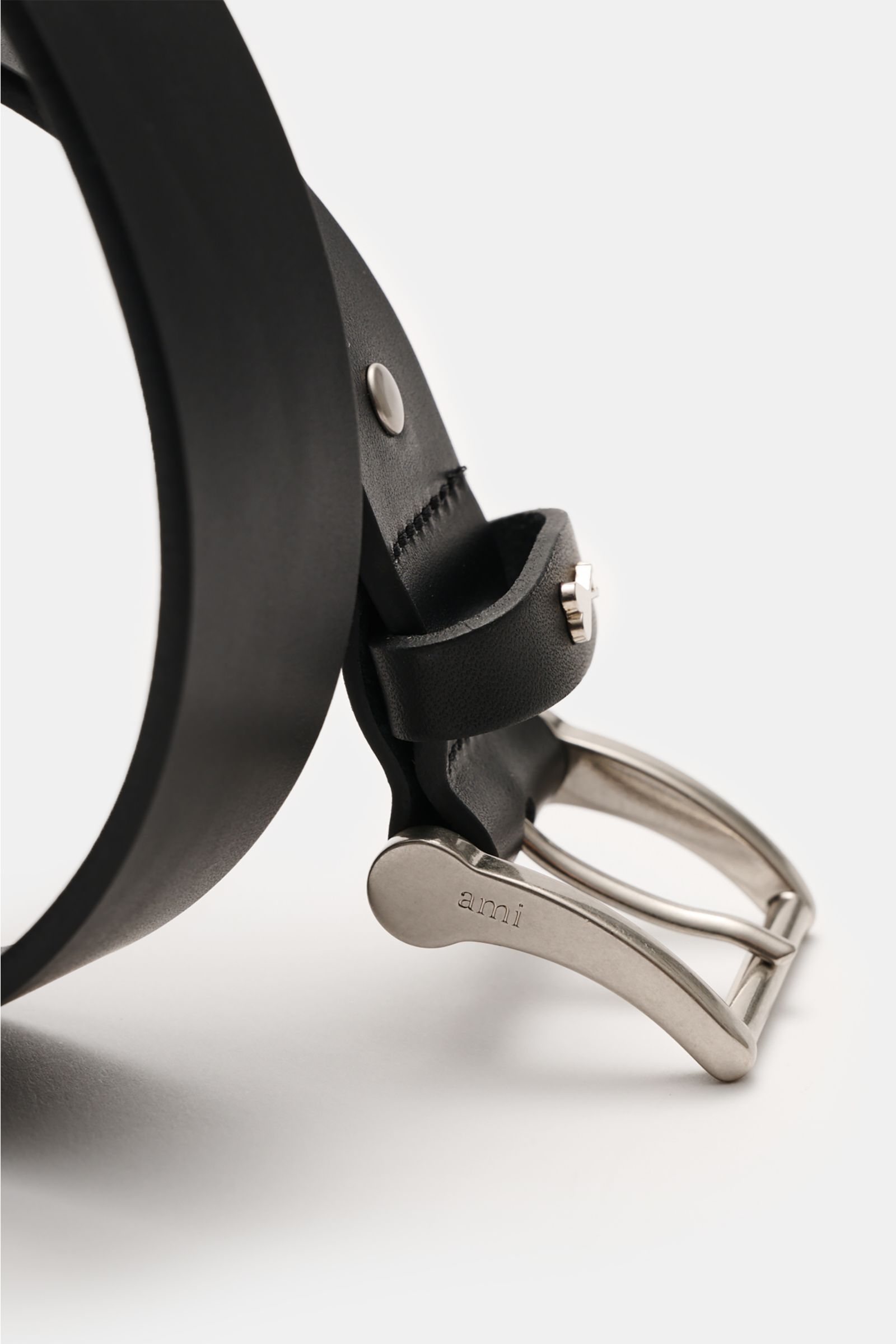 Close-up side view of Ami Paris Gürtel 'Paris' schwarz showing black smooth leather strap and silver brass pin buckle engraved with 'ami'.

Zeitloses Accessoire: Der 'Paris' Gürtel von AMI PARIS erweist sich als vielseitiges Essential für stilvolle Out