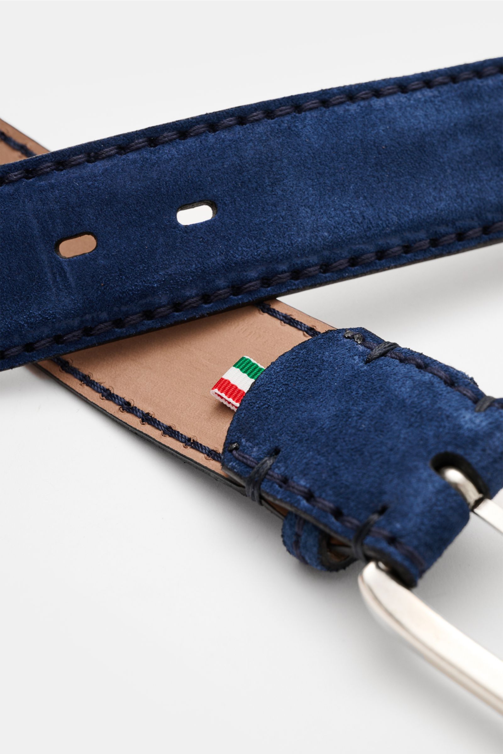 Close-up perspective of the Fausto Colato Veloursledergürtel dunkelblau, showcasing its rich dark blue suede leather, brass prong buckle, and a passing loop, with visible Italian flag detail on tan leather interior. Feinste Qualität von FAUSTO COLATO: mit