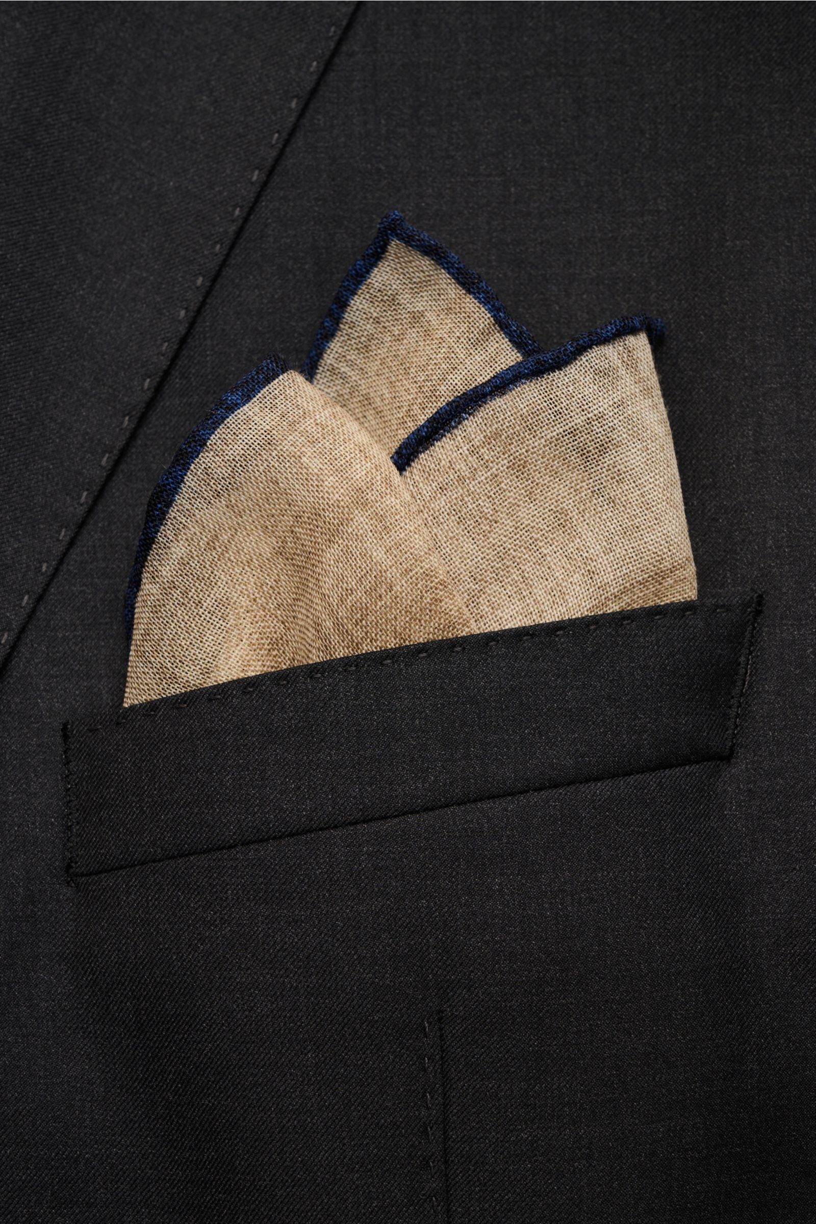 Rosi Collection Einstecktuch beige/navy aus reiner Wolle, weicher Griff, handrollierte Kanten in Kontrastfarbe, Made in Italy, ca. 30x30 cm, von vorne in dunkler Jackentasche.