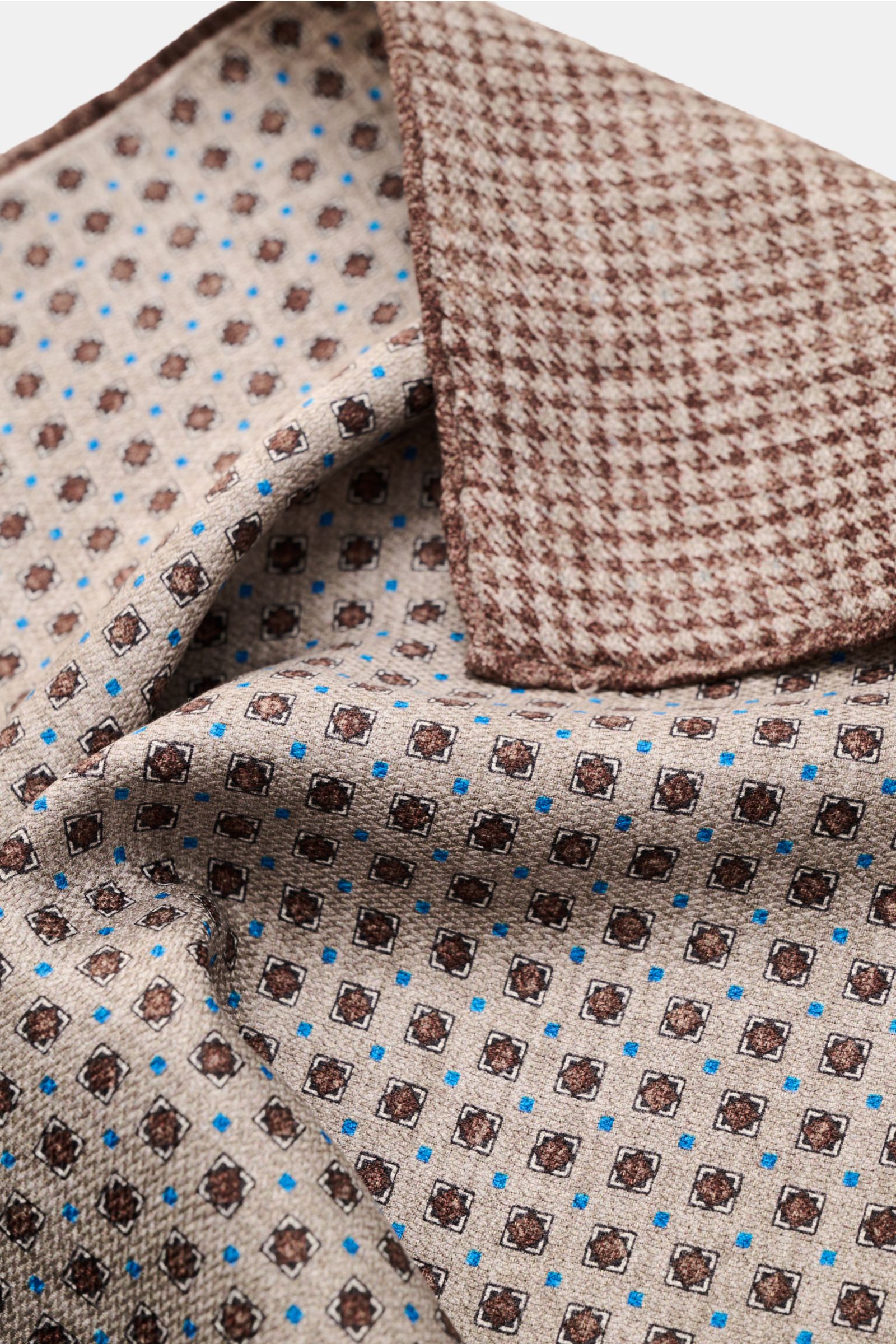Rosi Collection Einstecktuch 'Easy' grau/dunkelbraun/blau gemustert aus reiner Seide, geometrisch, Hahnentritt-Rückseite, rollierte Kanten, Nahaufnahme schräg von oben.