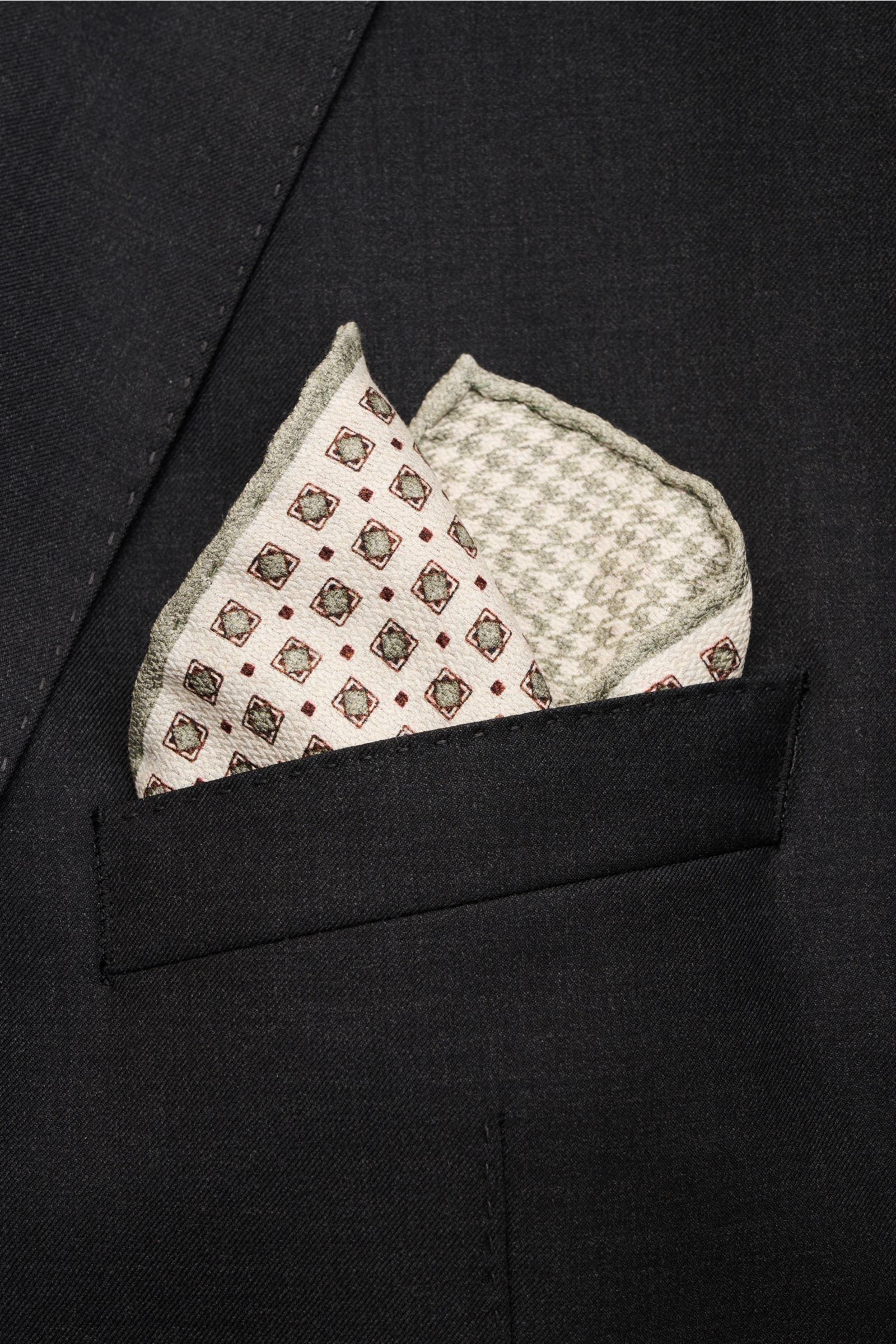 Rosi Collection Einstecktuch 'Easy' creme/graugrün/bordeaux gemustert aus reiner Seide, geometrisch, Hahnentritt-Rückseite, rollierte Kanten, fotografiert in Nahaufnahme im Sakko-Brusttaschen-Einsatz.