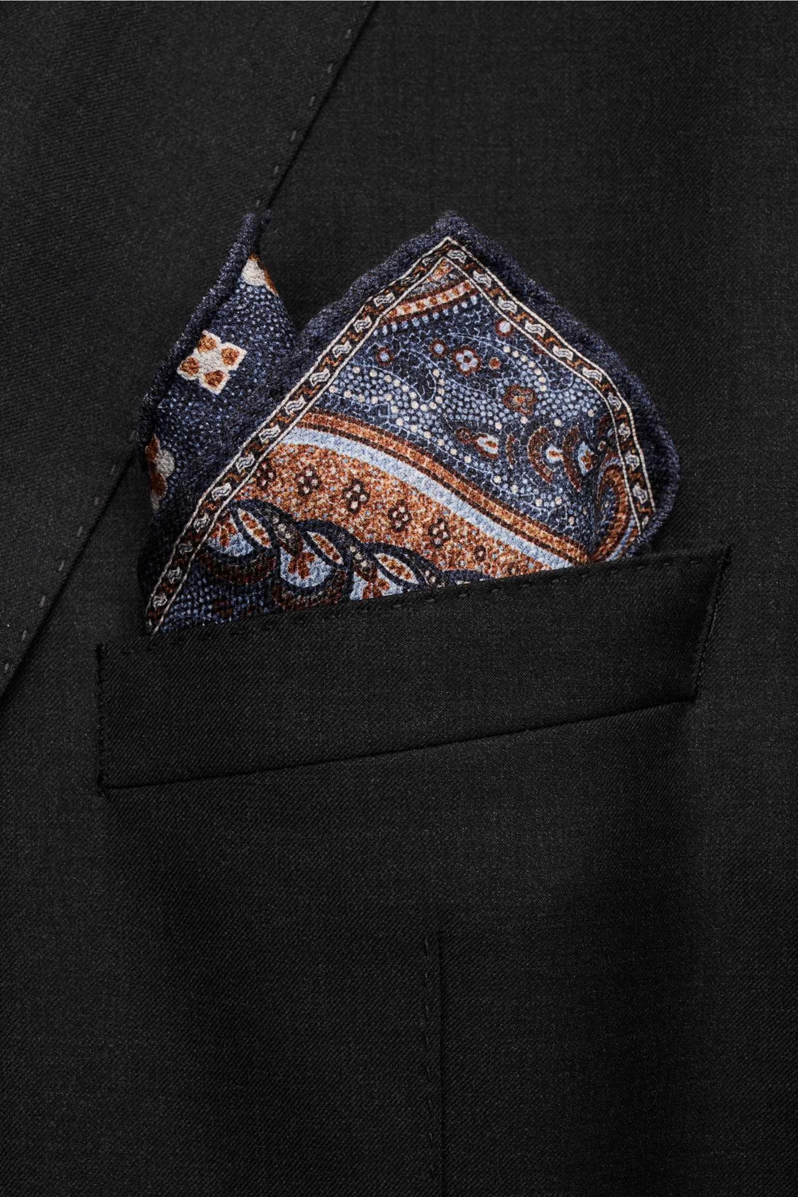 Rosi Collection Seiden-Einstecktuch 'Easy' graublau/hellblau/braun gemustert, reine Seide, Paisley-Muster mit Borte, handrollierte Kanten, Medaillon-Rückseite, soft, 31x31 cm, Made in Italy, von vorne in dunkler Jackettasche.