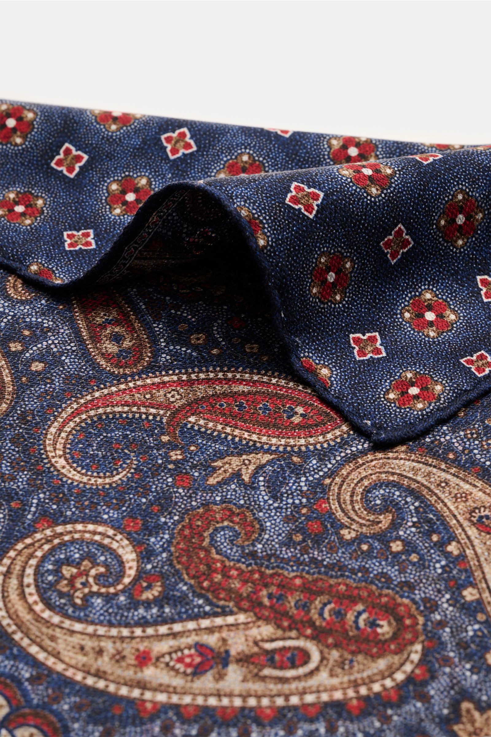 Rosi Collection Seiden-Einstecktuch 'Easy' dunkelblau/dunkelrot/braun gemustert, reine Seide, Paisley-Muster mit Borte, Rückseite Medaillon-Muster, handrollierte Kanten, soft, 31x31 cm, Made in Italy, Detailaufnahme von oben schräg.