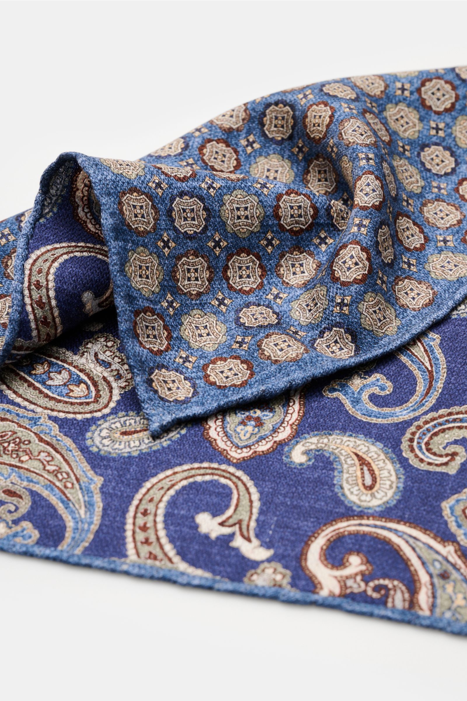 Rosi Collection Seiden-Einstecktuch 'Easy' blau/braun/graugrün gemustert, aus reine Seide, Medaillon- und Paisley-Print, handrollierte Kanten, Made in Italy, ca. 30,5x30,5 cm, Detailaufnahme schräg von oben mit softem, geschmeidigem Griff.