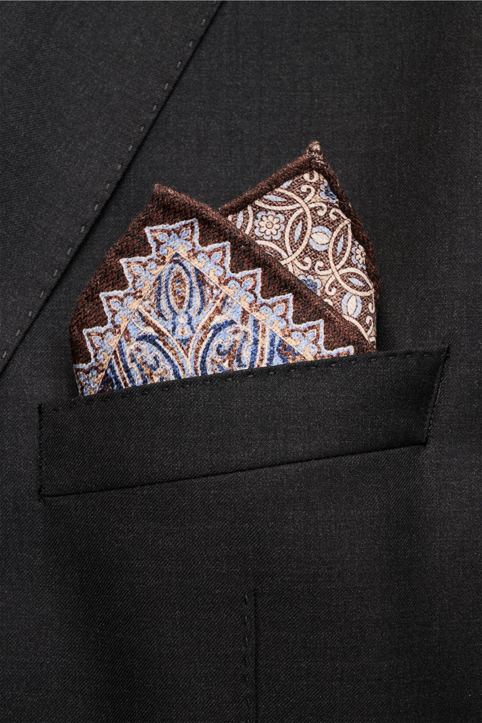 Rosi Collection Einstecktuch 'Easy' dunkelbraun/blau/weiß gemustert mit Paisley-Muster aus reiner Seide, Vorder- und Rückseite unterschiedlich, in schwarzer Sakkotasche, Nahaufnahme.