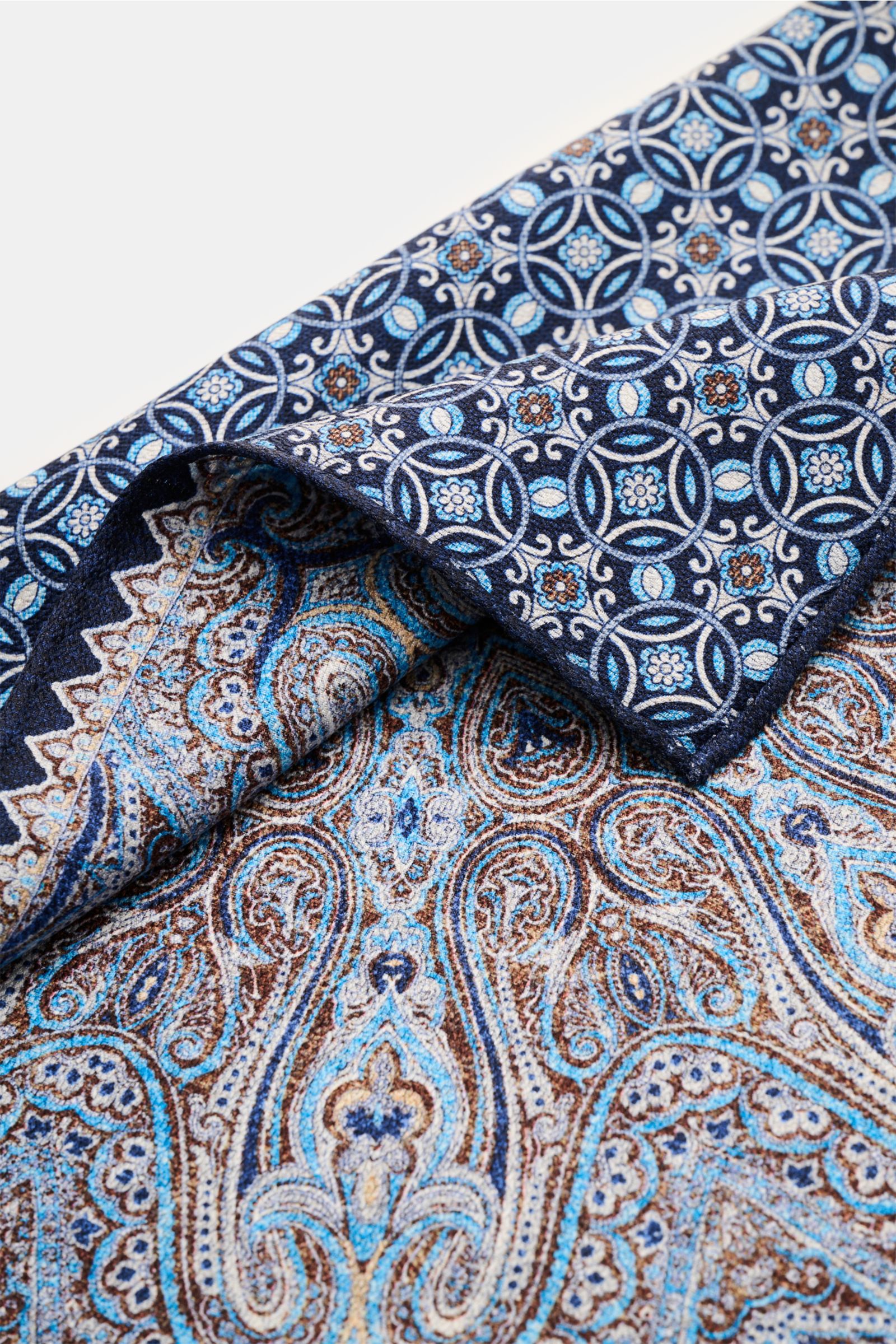 Close-up top view of the Rosi Collection Pocket square 'Easy' navy/blue/white patterned with modern paisley and rolled edges in pure silk.

Description: 
Elegant and eye-catching: With its modern paisley pattern, this pocket square in pure silk by ROSI