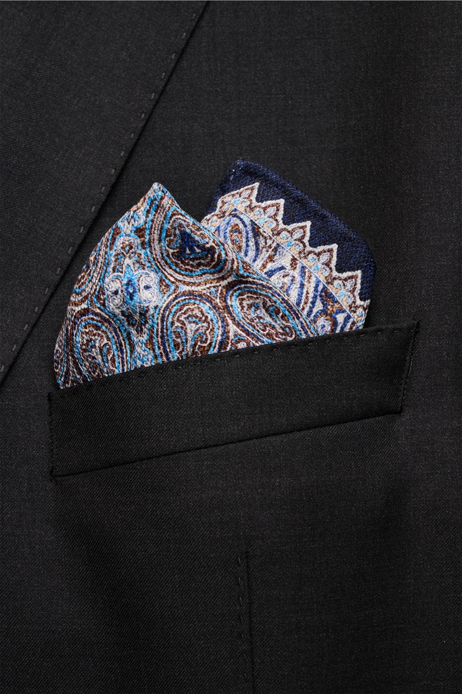 Close-up front view of the Rosi Collection Pocket square 'Easy' navy/blue/white patterned silk pocket square with paisley design, folded in a black jacket pocket.

Elegant and eye-catching: With its modern paisley pattern, this pocket square in pure si