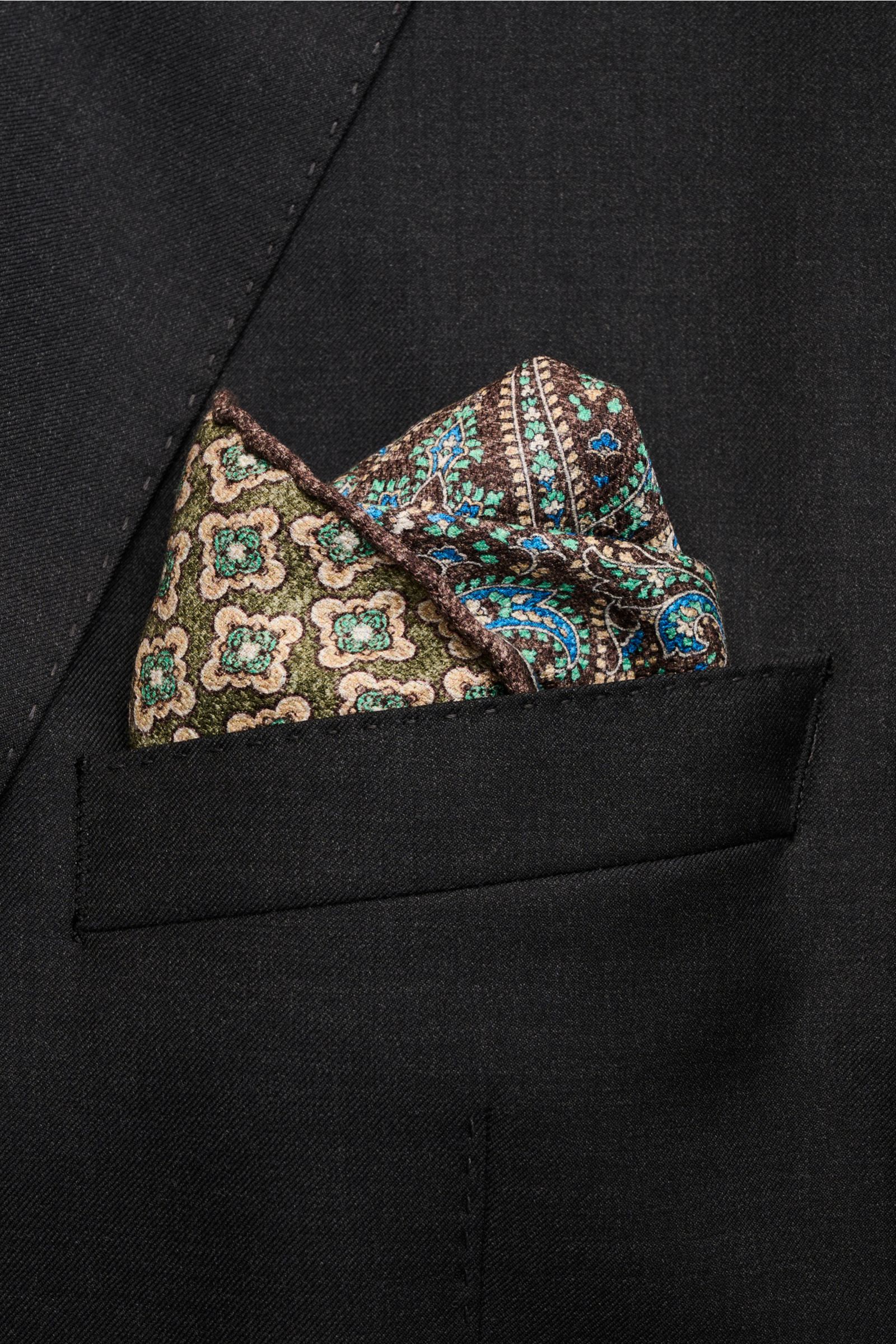 Rosi Collection Seiden-Einstecktuch 'Easy' dunkelbraun/oliv/azurblau gemustert, reine Seide, soft, Paisley- und Kachel-Muster, Medaillon-Rückseite, handrolliert, Made in Italy, 31x31 cm, aus Brusttasche, seitliche Nahaufnahme.