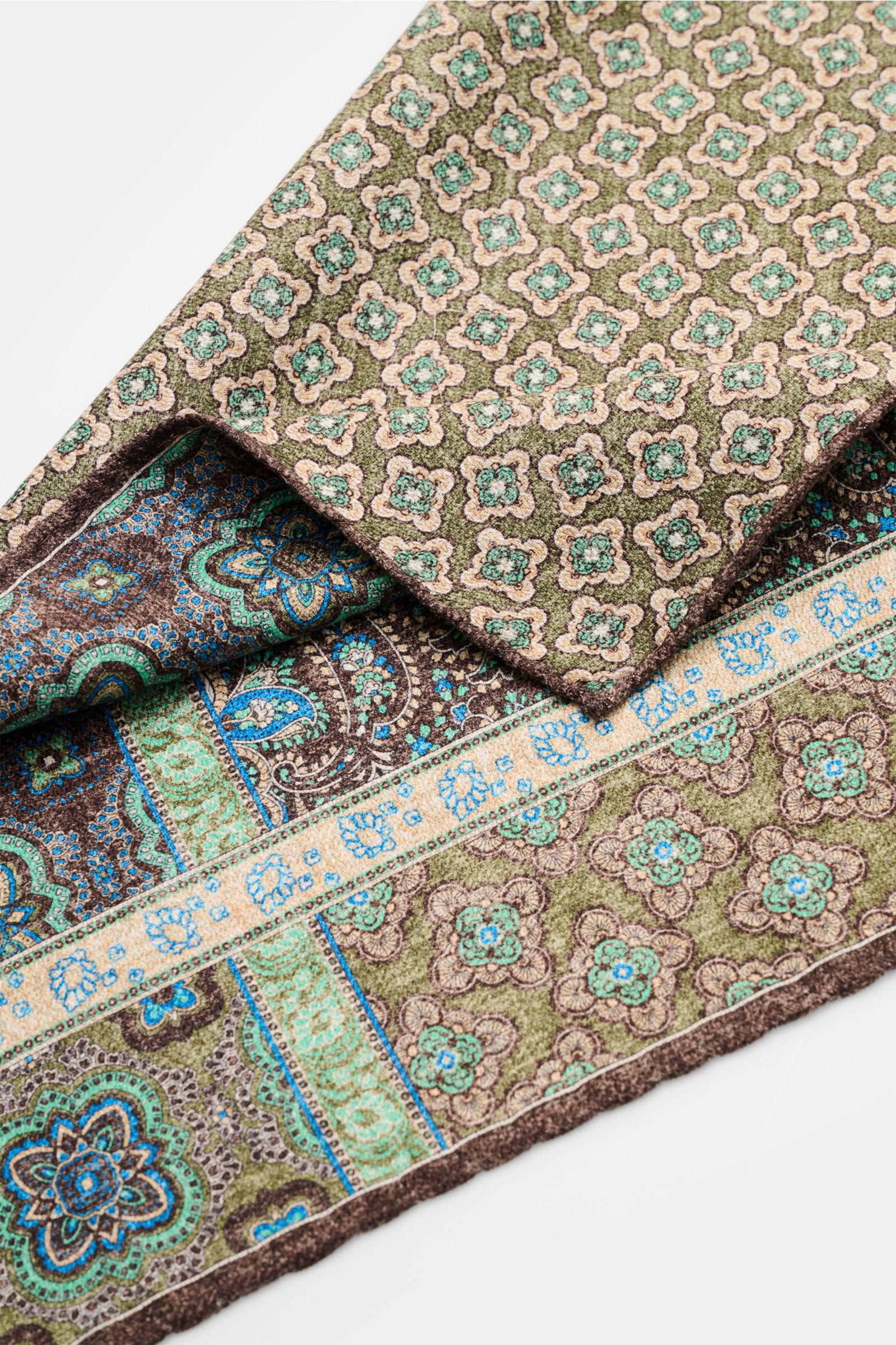 Rosi Collection Seiden-Einstecktuch 'Easy' dunkelbraun/oliv/azurblau gemustert, reine Seide, Paisley- und Kachel-Muster mit Borte, handrollierte Kanten, weiche Haptik, Rückseite Medaillon-Print, Maße 31x31 cm, Made in Italy, Nahaufnahme von schräg oben.